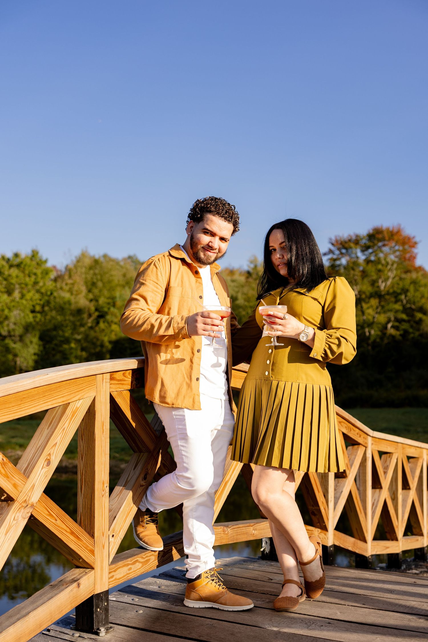 People sharing drinks and conversation on a wooden bridge deck on a sunny autumn day.