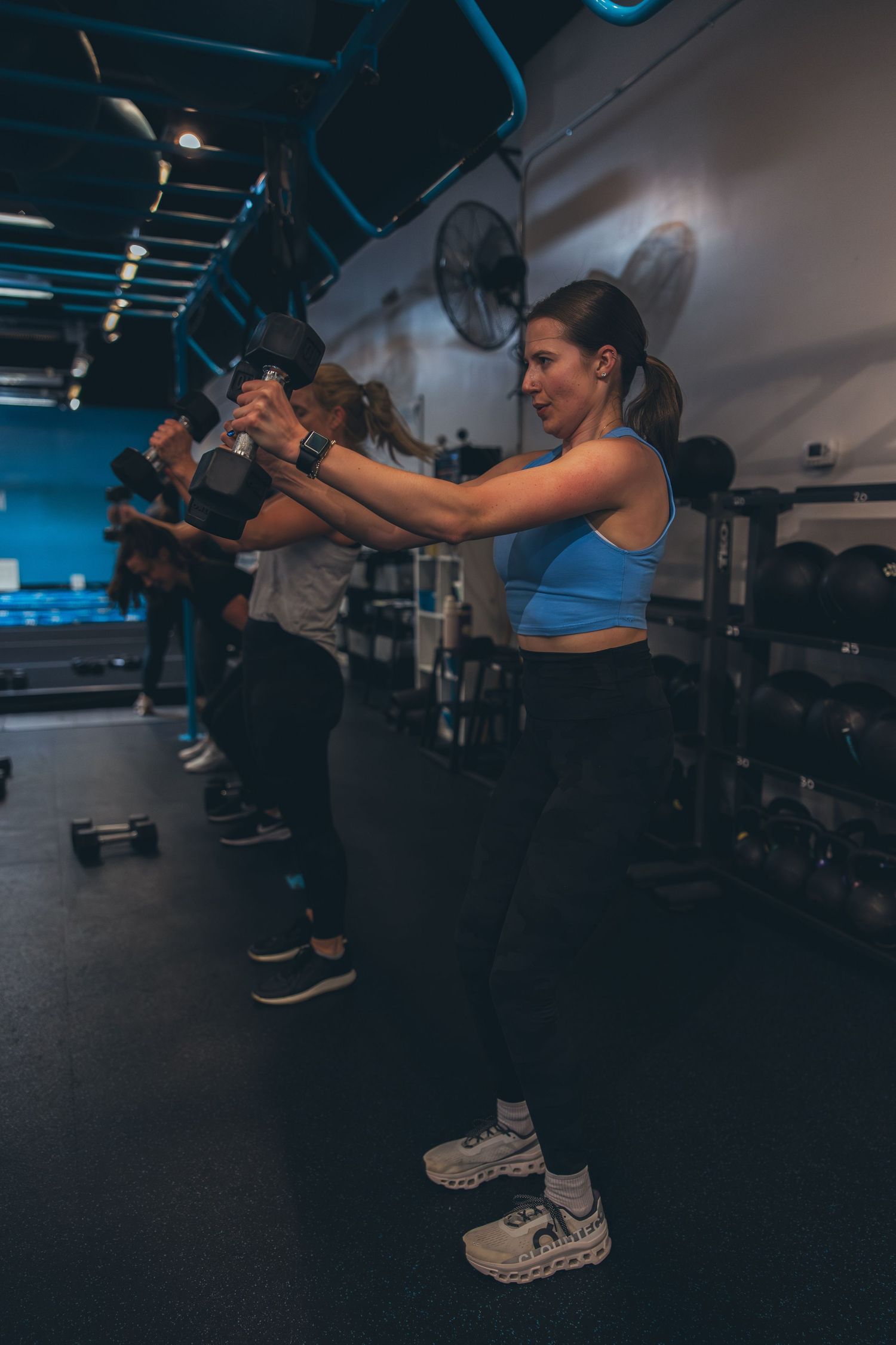 Athletes perform synchronized kettlebell exercises in a modern fitness facility.