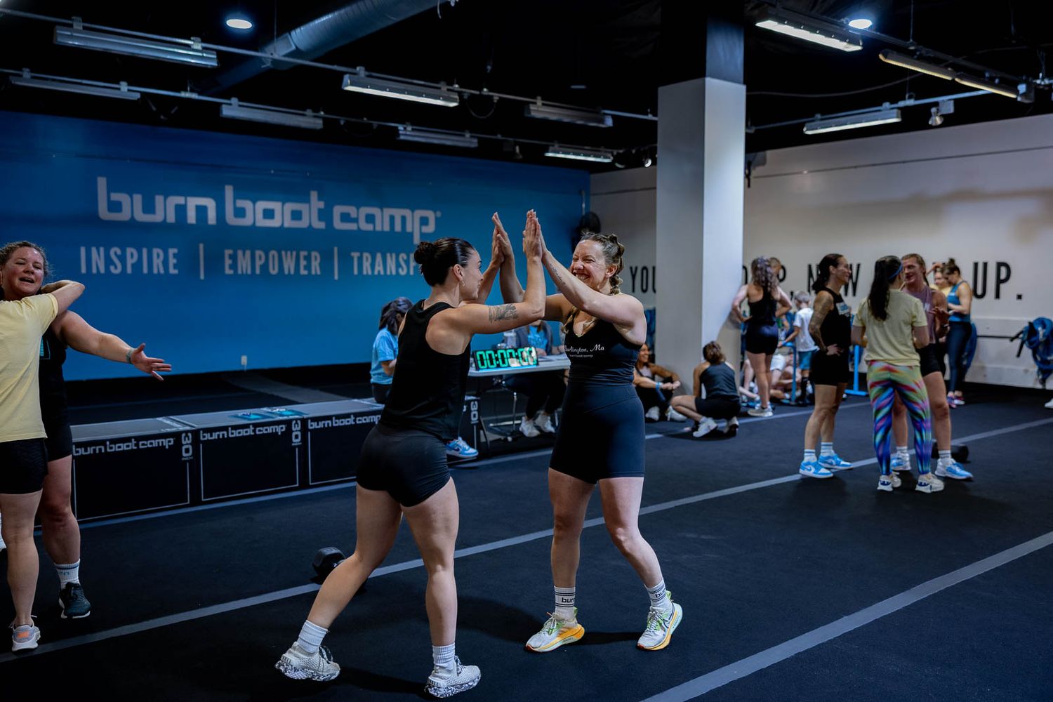 Athletes high-five each other during an energetic fitness class at Burn Boot Camp.