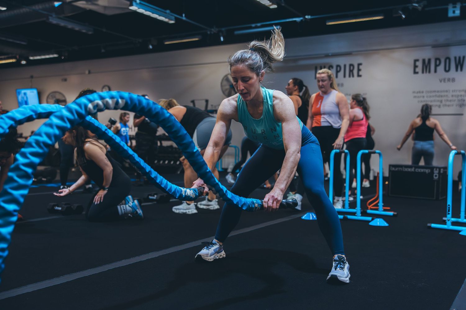 Athletes perform coordinated battle rope exercises during a group fitness class.
