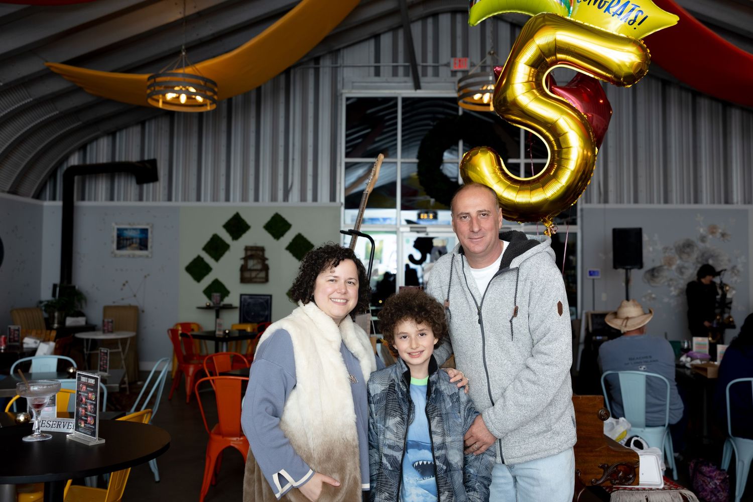 People gather at an indoor party or celebration with festive decorations and lighting.
