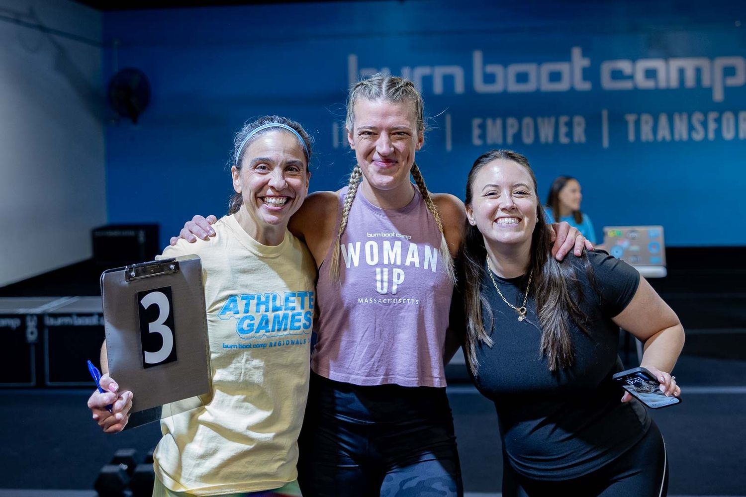 Three athletes celebrate together after a workout at a boot camp fitness class.