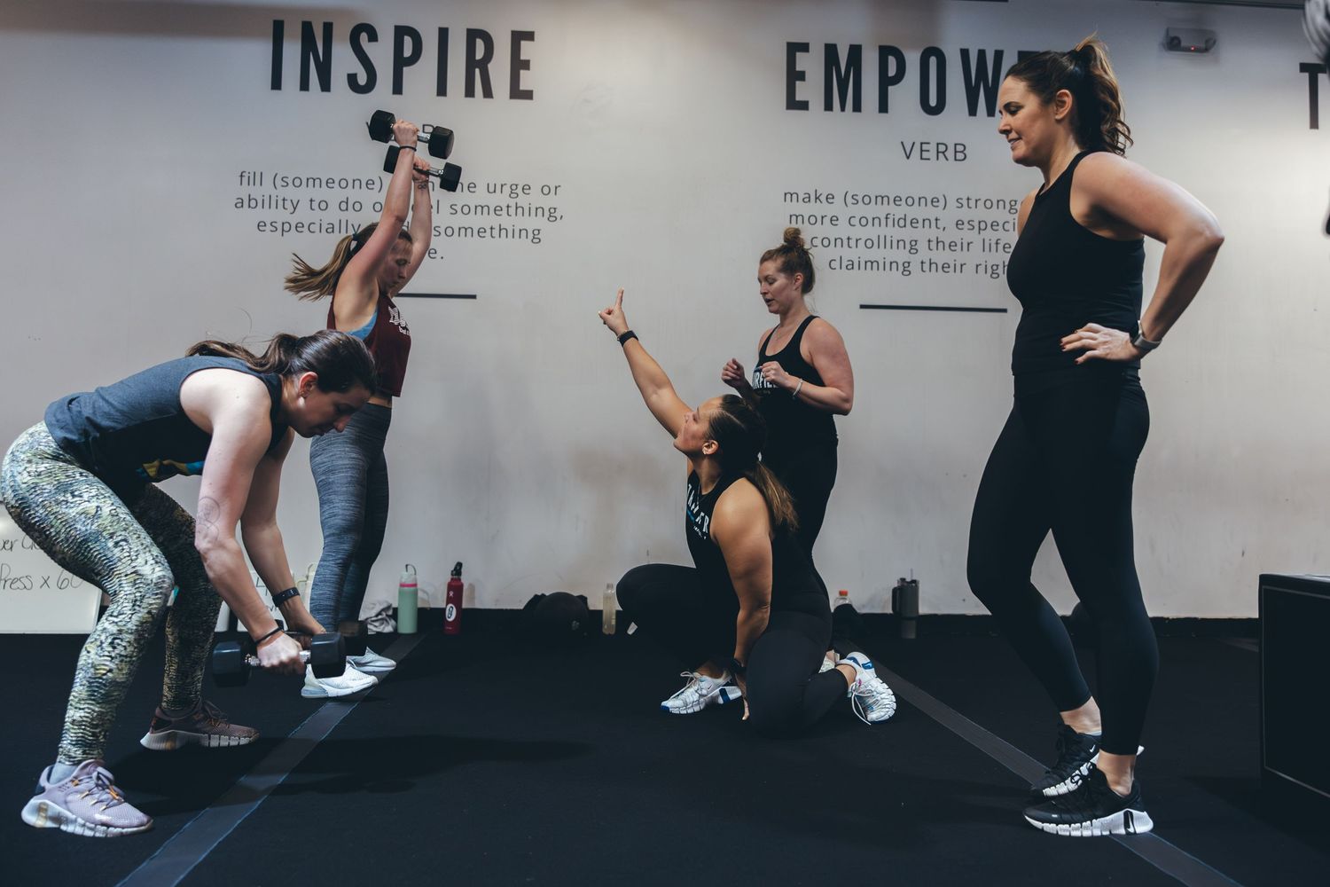 Dynamic group workout session with participants doing various exercises in a modern fitness studio.