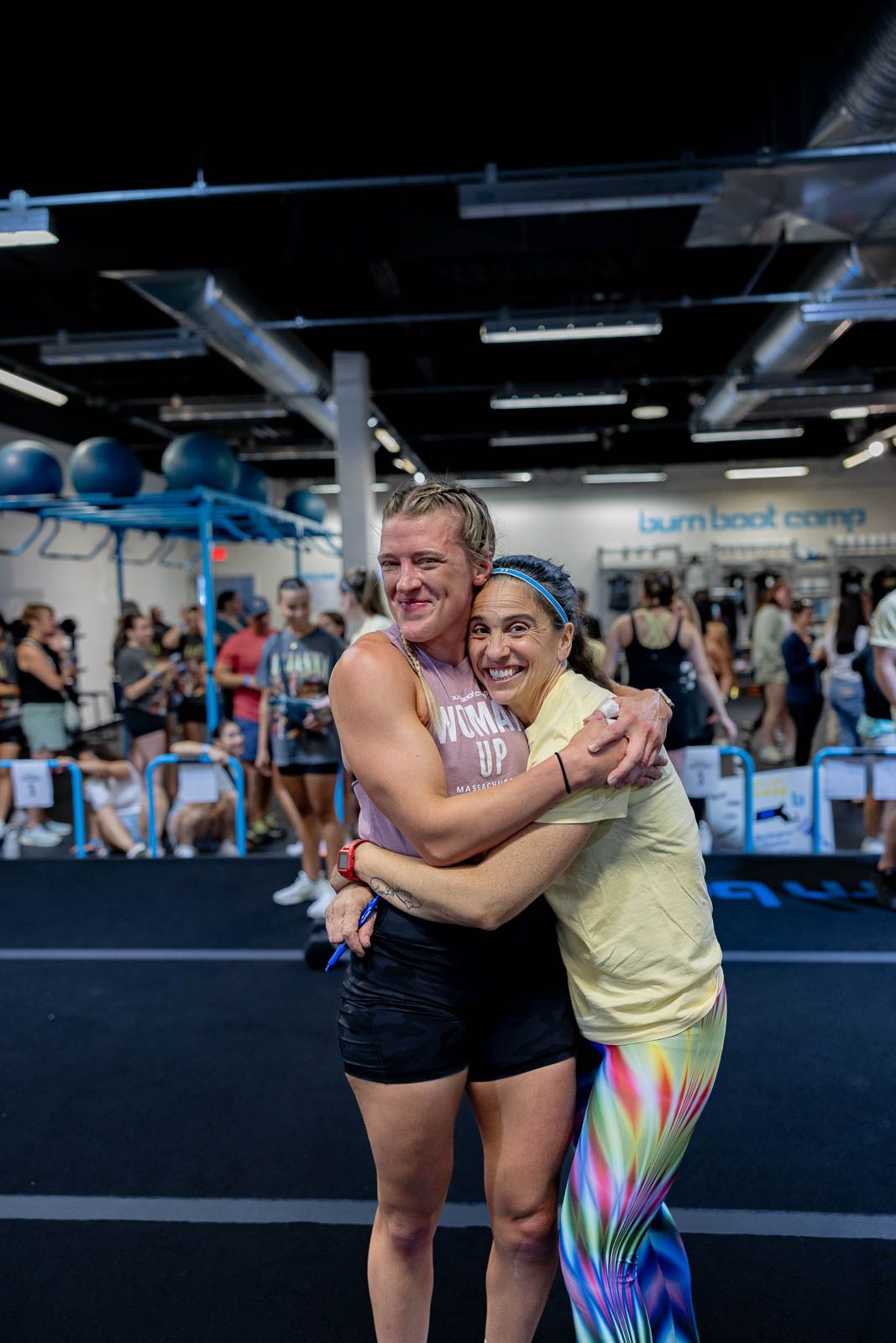 Two workout partners share a celebratory embrace after exercising at a fitness studio.