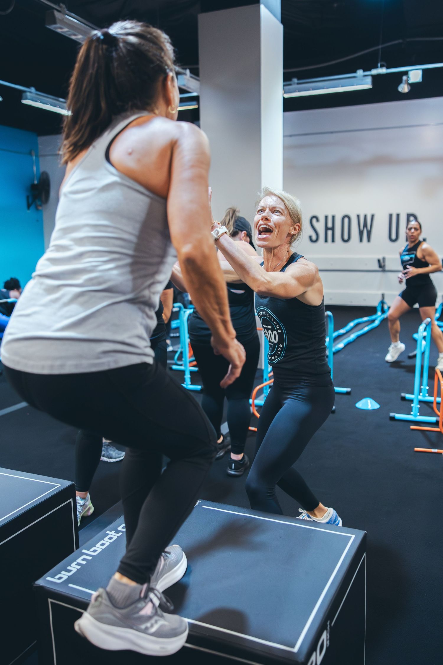 Two people exercising on elevated platforms during a high-energy fitness class.