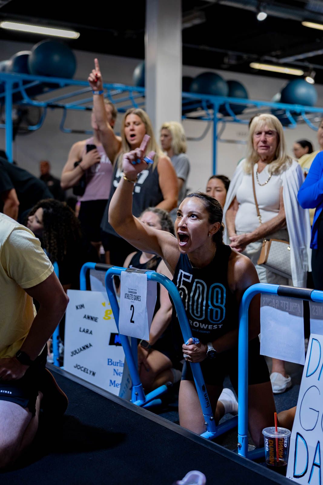 Enthusiastic fans cheer and point from the stadium stands during an intense sporting event at an indoor arena.