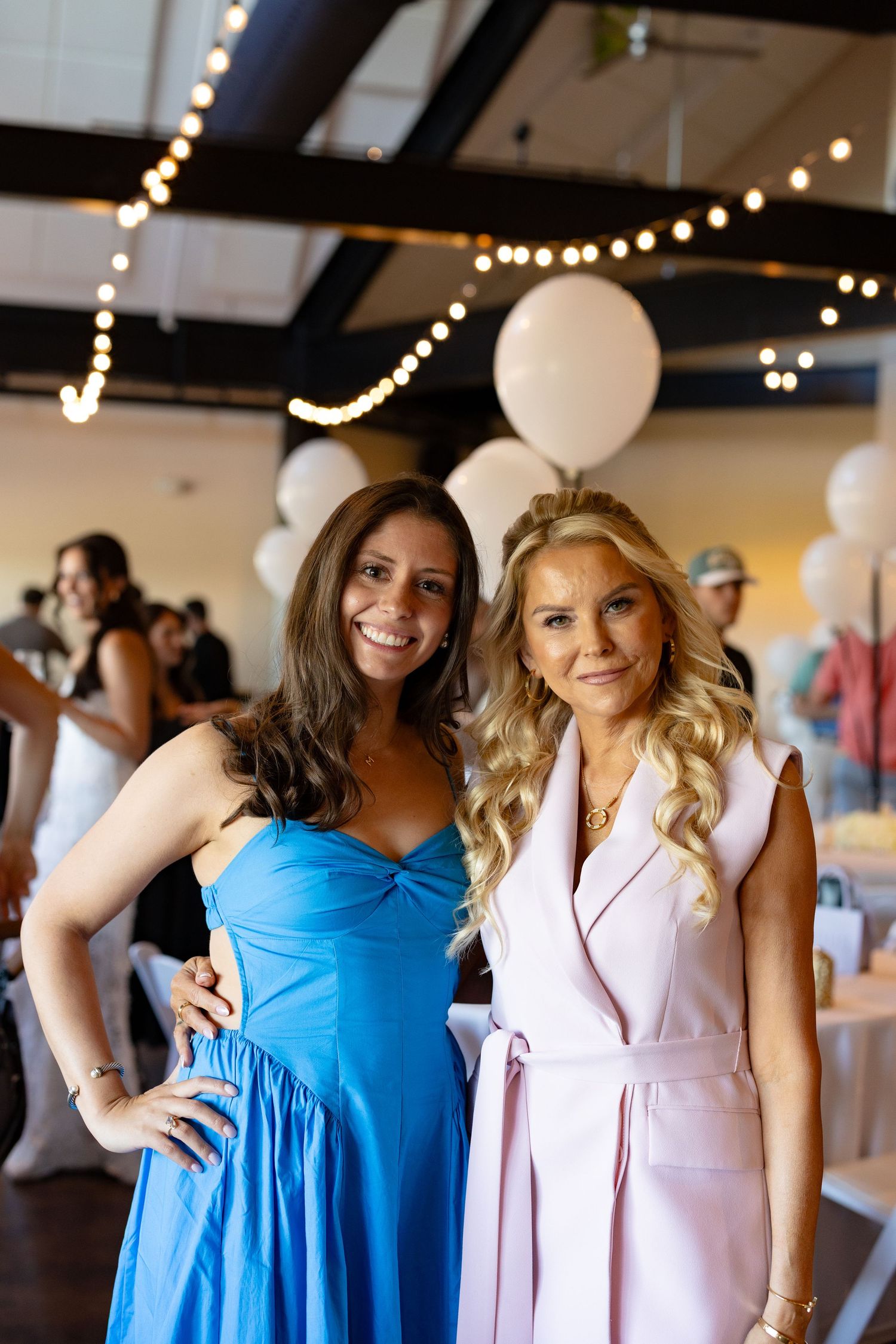 A group photographed at an indoor venue with string lights and balloons decorating the space.