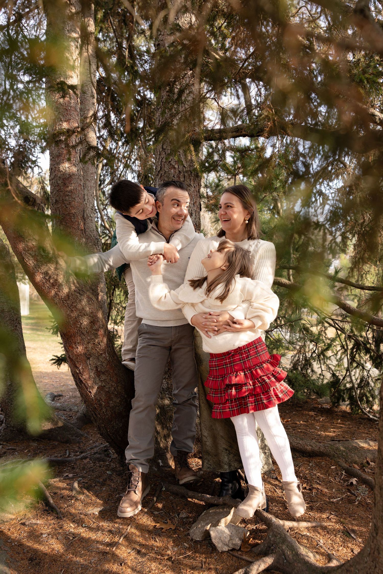 A romantic couple shares tender moments together under a large tree in a natural outdoor setting.