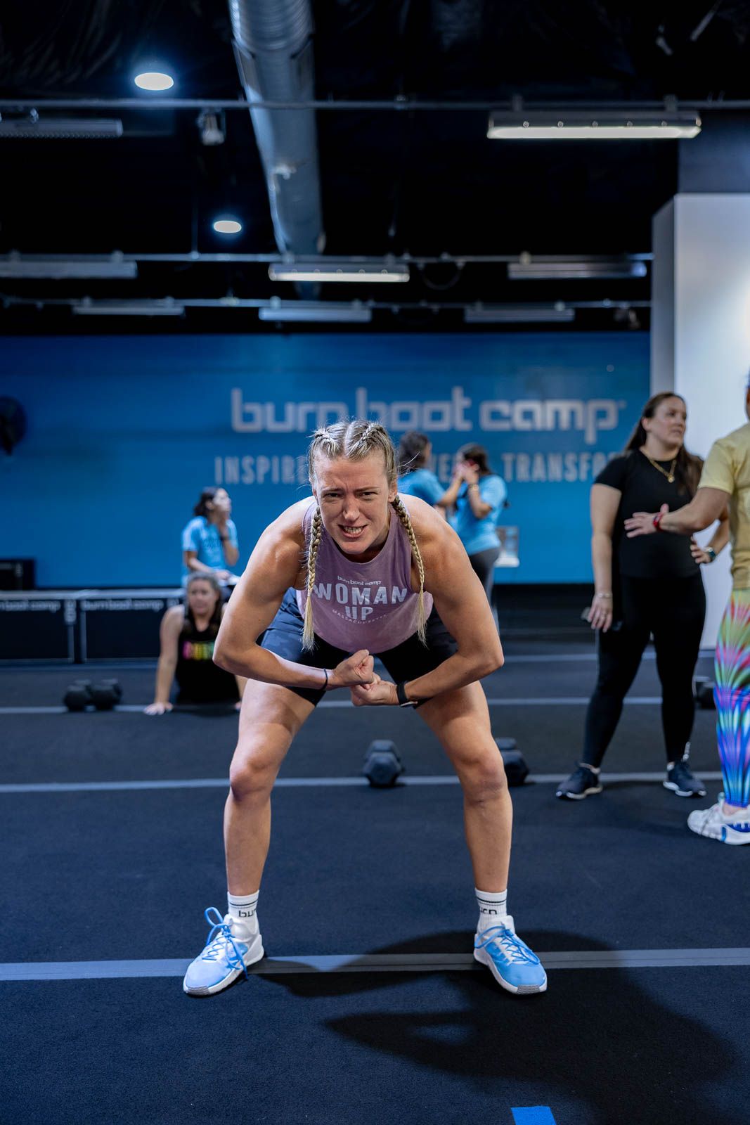 Athlete in workout gear catches their breath during an intense training session at Burnt Boot Camp fitness facility.