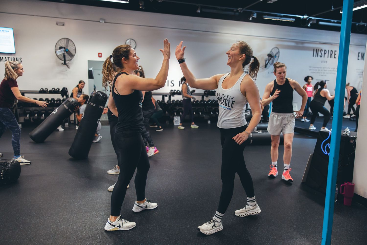 Training partners give each other a high-five during a workout session in a gym.