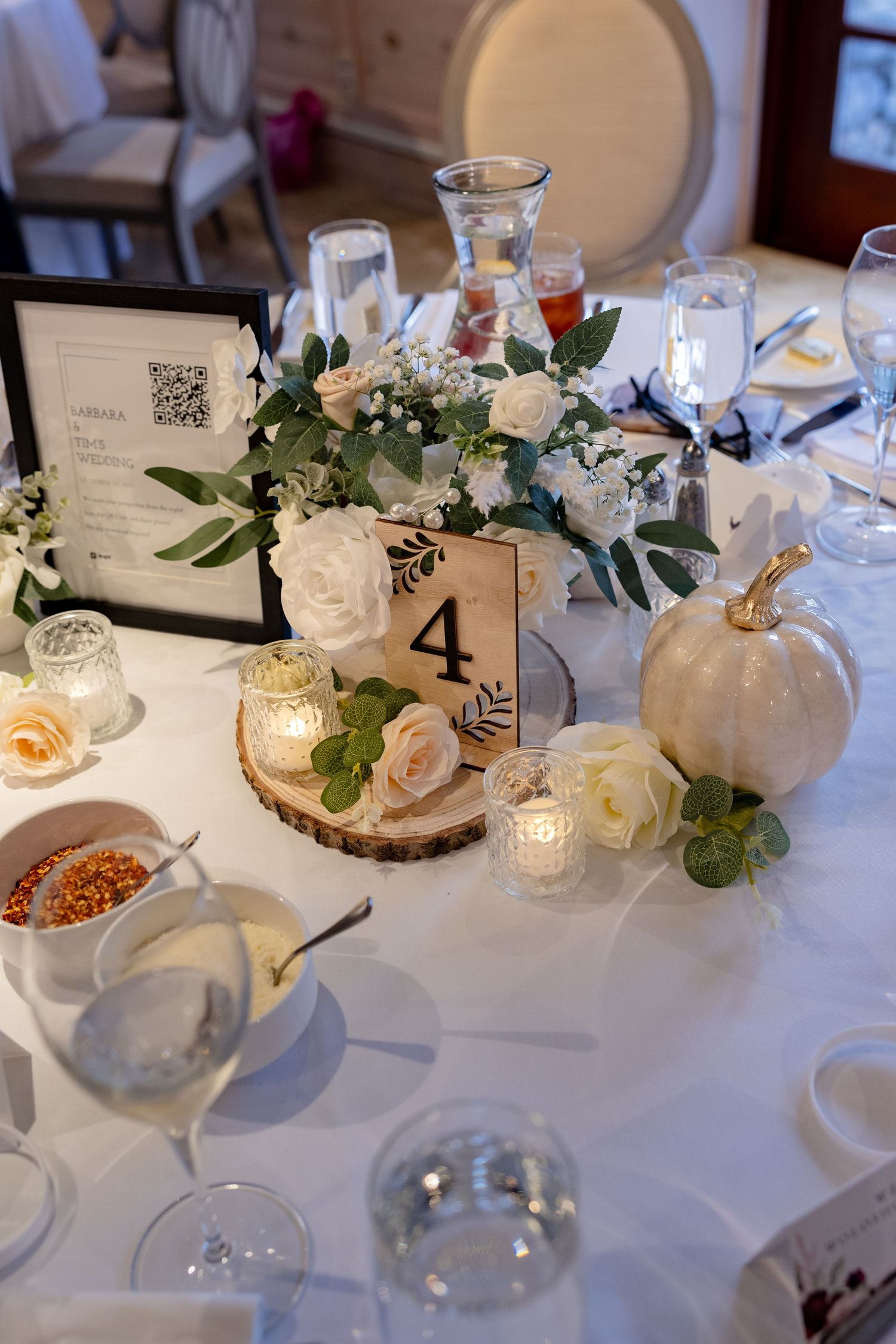 Elegant wedding reception table settings with white linens, candlelight, floral centerpieces and table number four displayed.