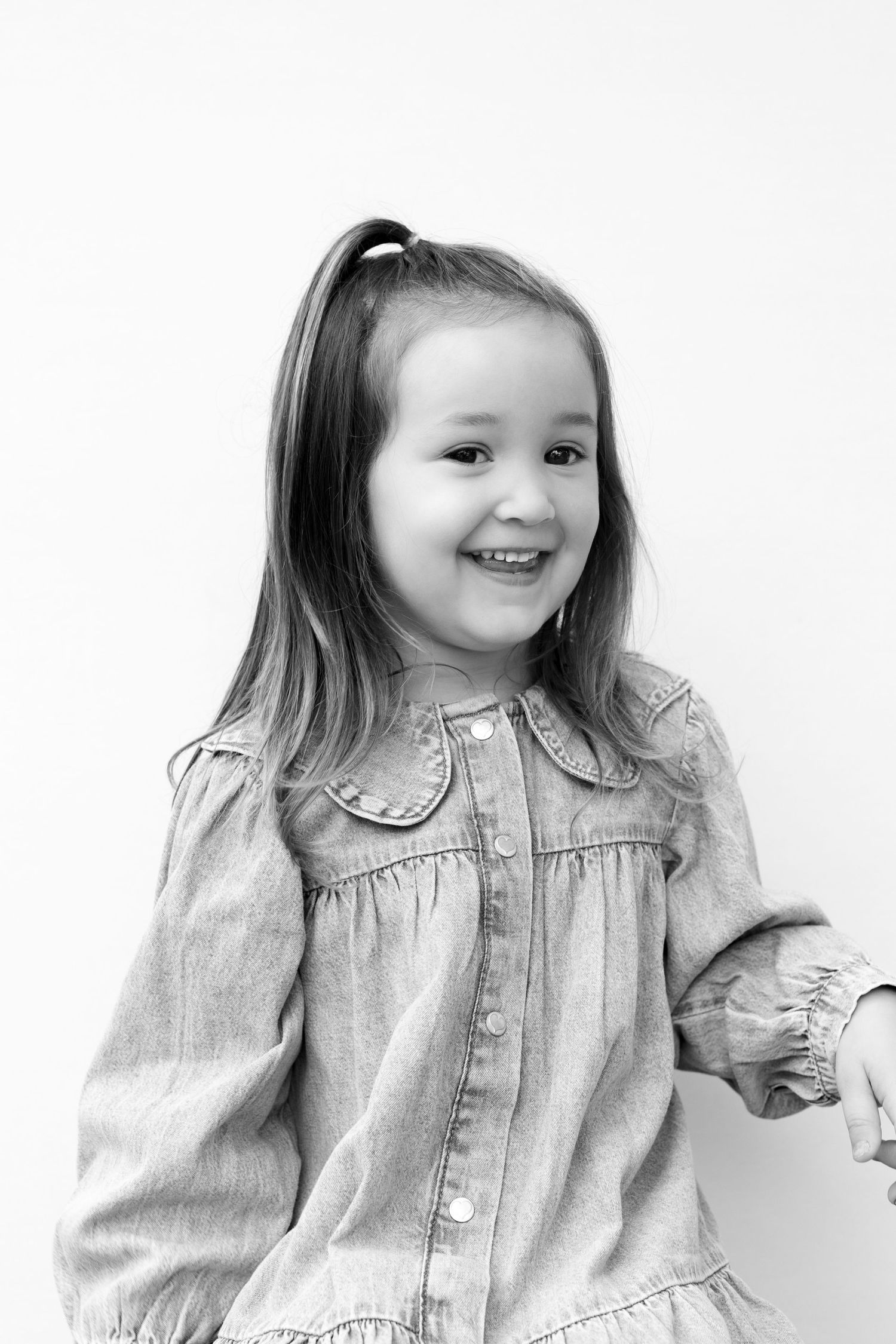 Four black and white photos showing a child in a light colored denim jacket making different playful expressions.