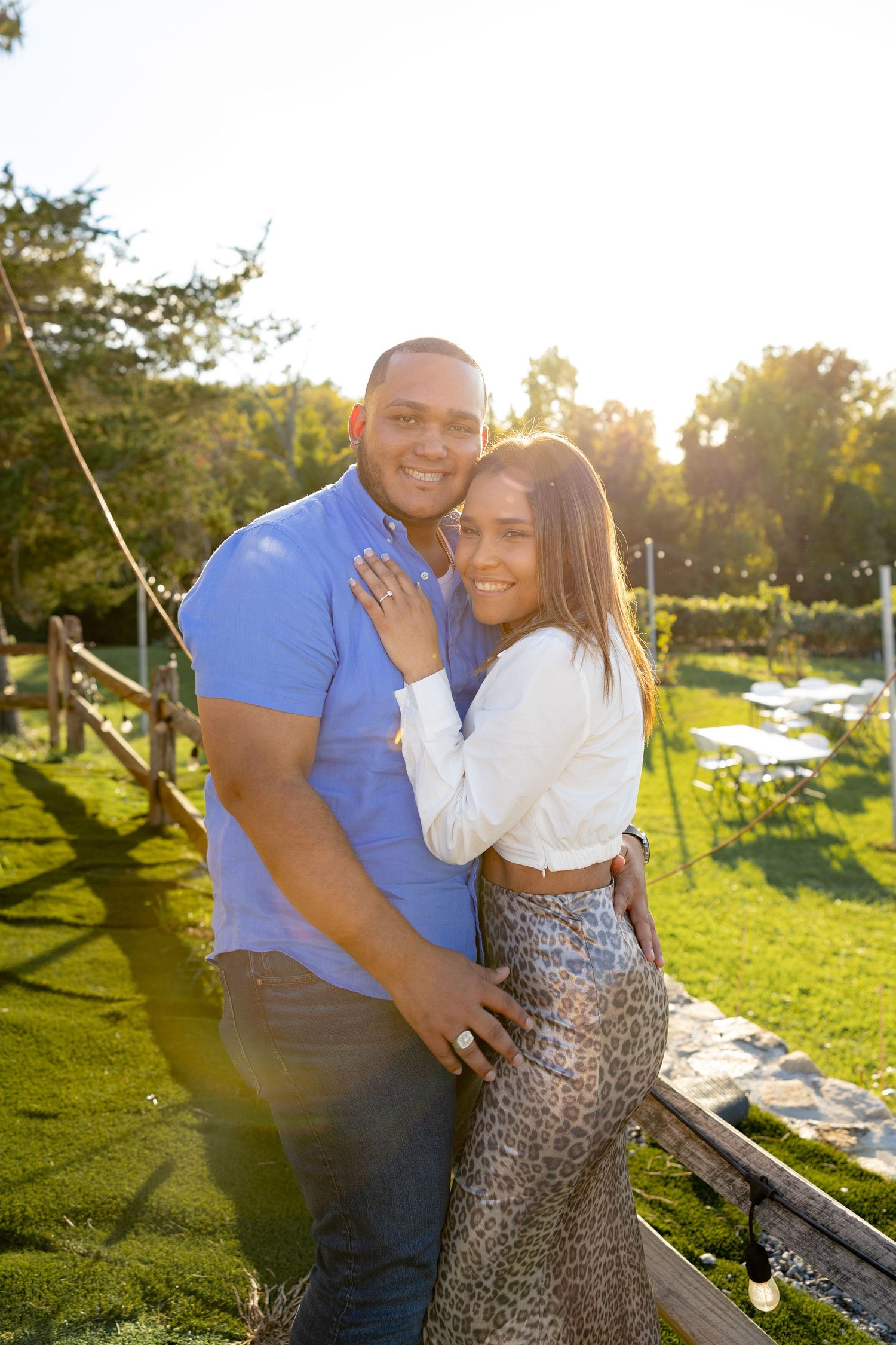 A romantic couple embraces on a wooden deck during golden hour sunset.