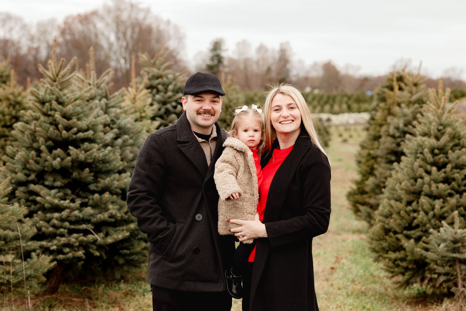 A couple shares a joyful moment together while shopping for Christmas trees at a festive tree farm.