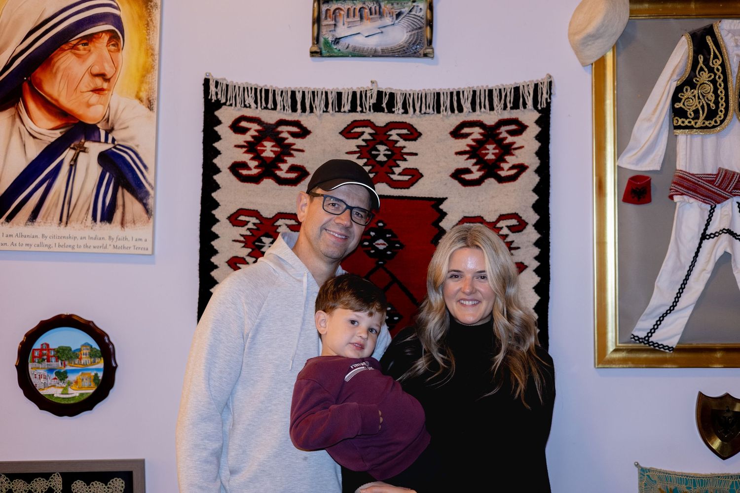 People gathered in a room with various framed artwork and decorations hanging on white walls.