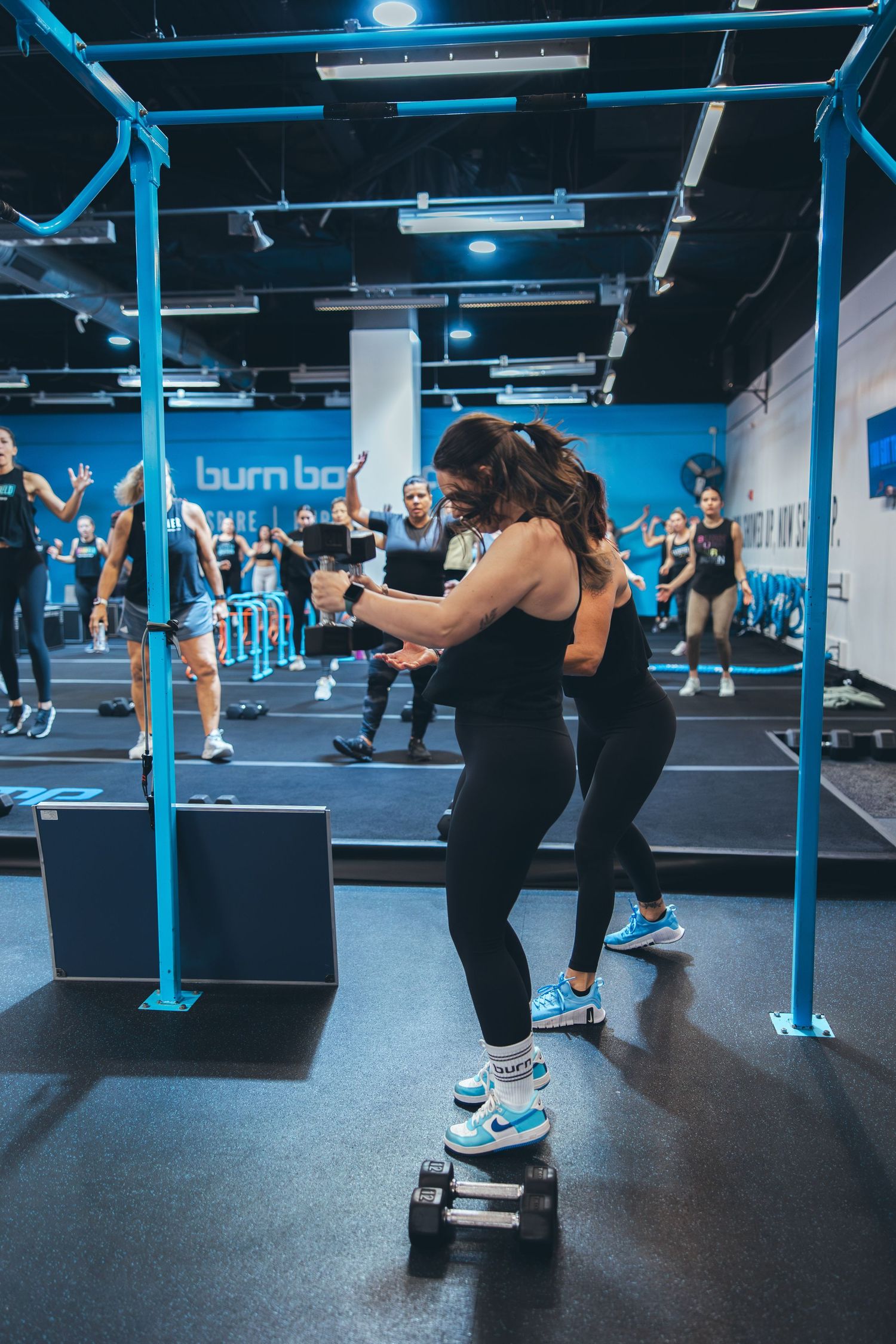 Fitness participants performing step exercises in blue-lit gym during group workout class.