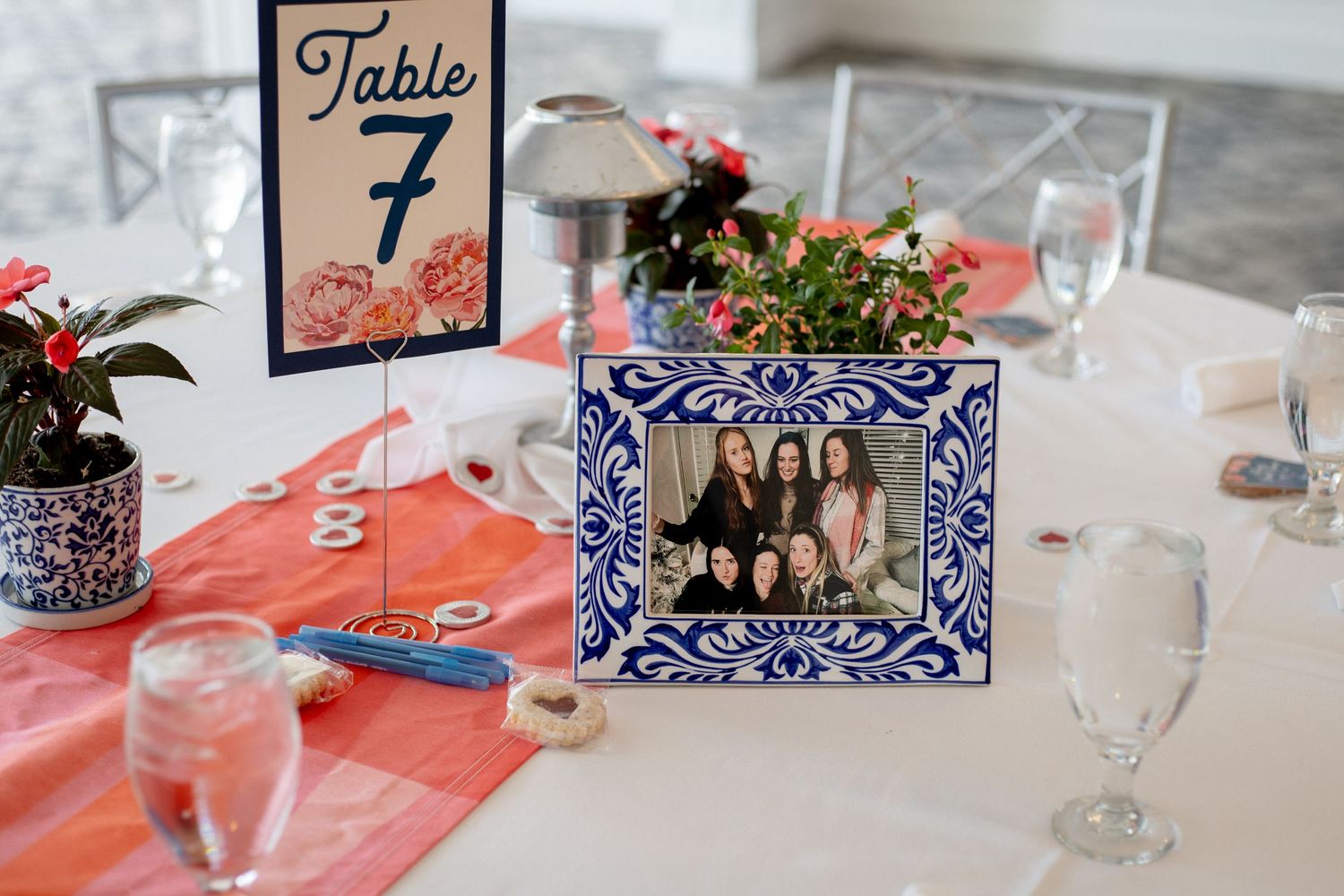 A wedding table setting with table number 7 and blue and coral decorations.