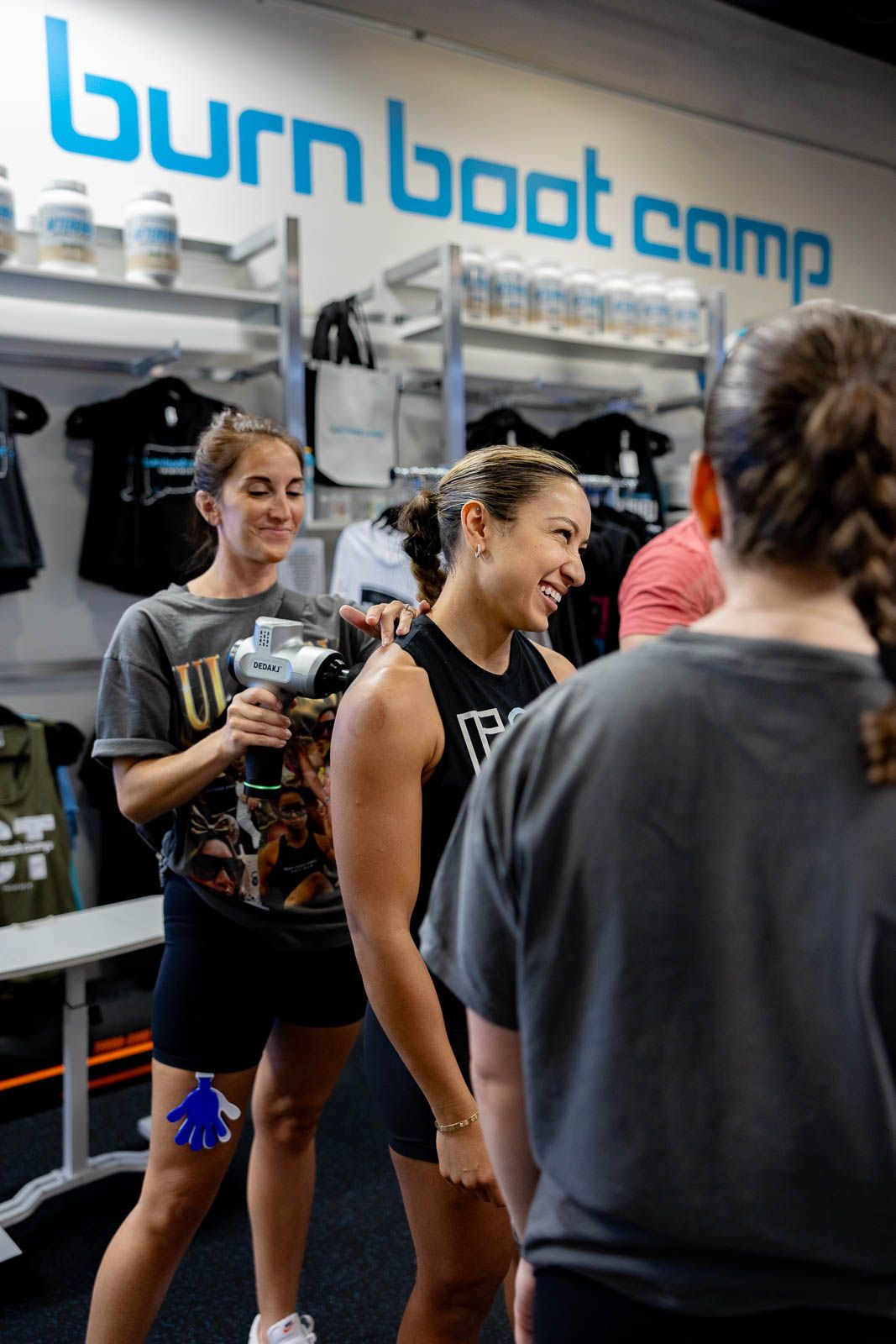 Fitness enthusiasts exercising together in a modern gym with blue branding on the wall.