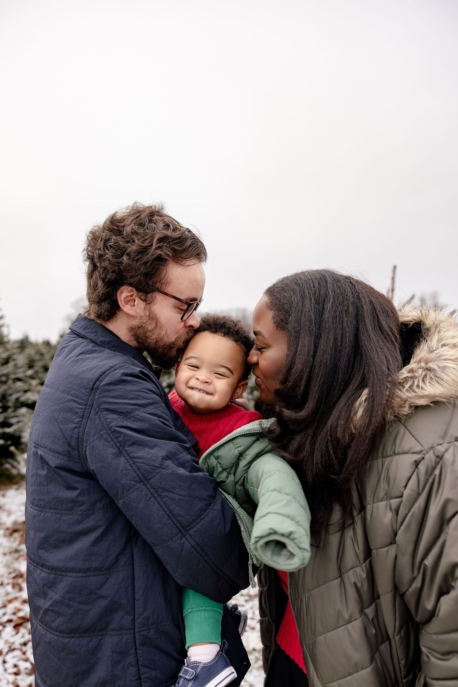 A family shares tender moments of affection and hugs outdoors in winter clothing.