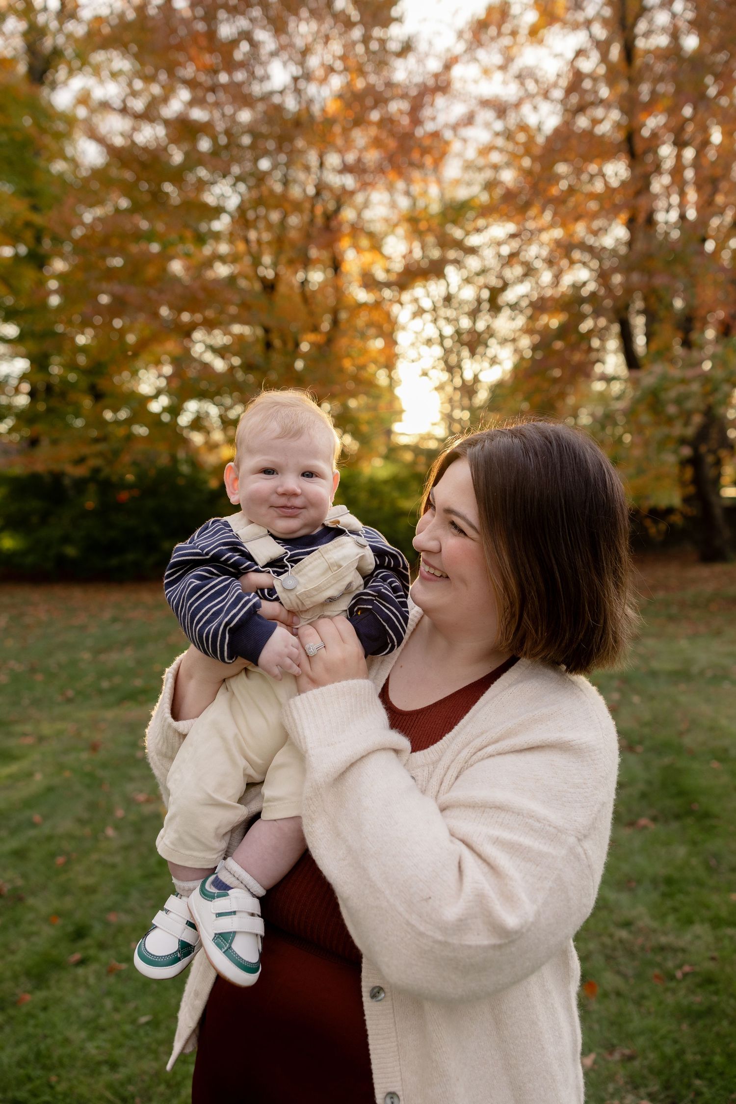 A joyful autumn outdoor photoshoot in a park with warm golden light filtering through fall foliage in the background.