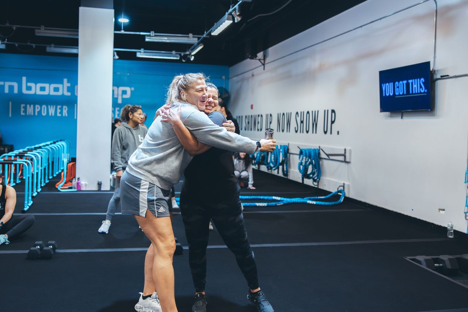 People exercising together in modern gym with motivational wall text.