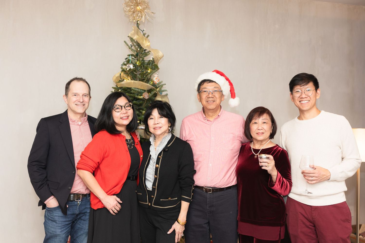 Group photo of people gathered around a decorated Christmas tree at a holiday celebration.