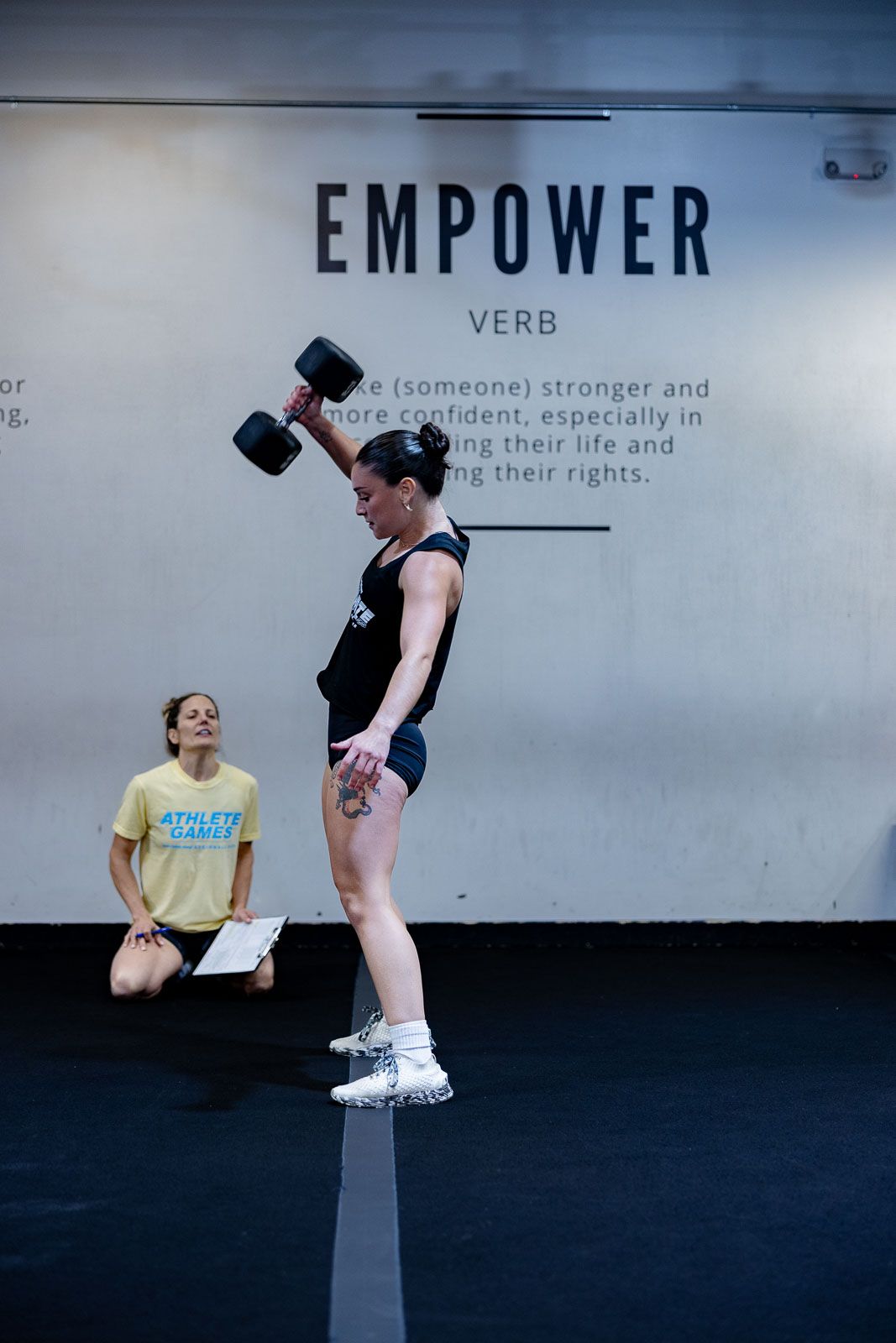 Athletes performing strength training exercises beneath 'EMPOWER' text on gym wall.