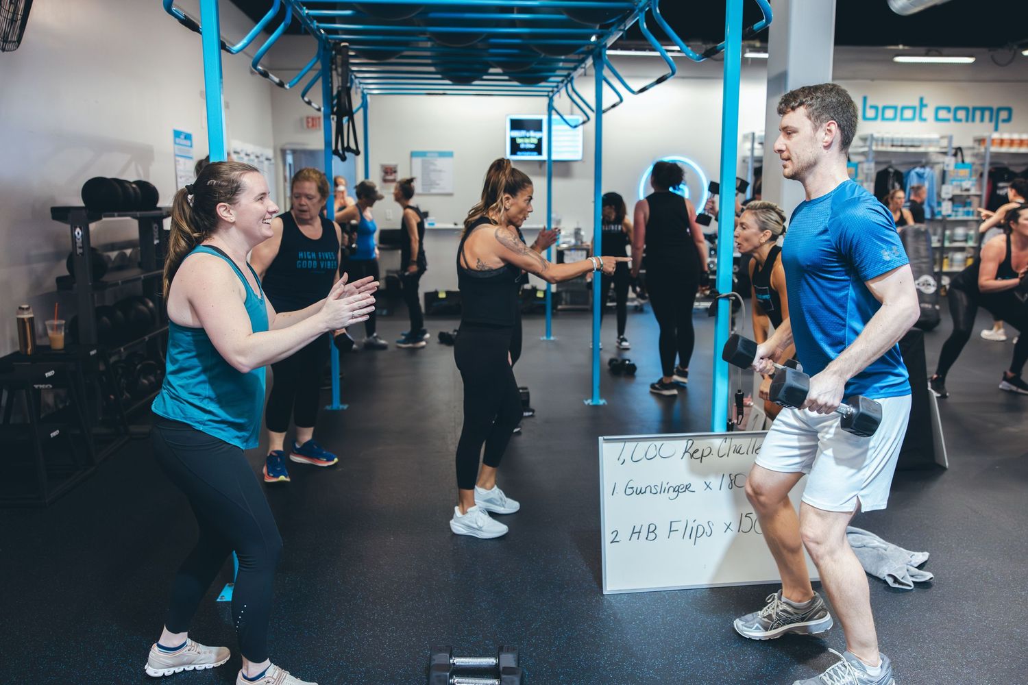 Fitness enthusiasts exercising in a blue-accented gym space during group training.