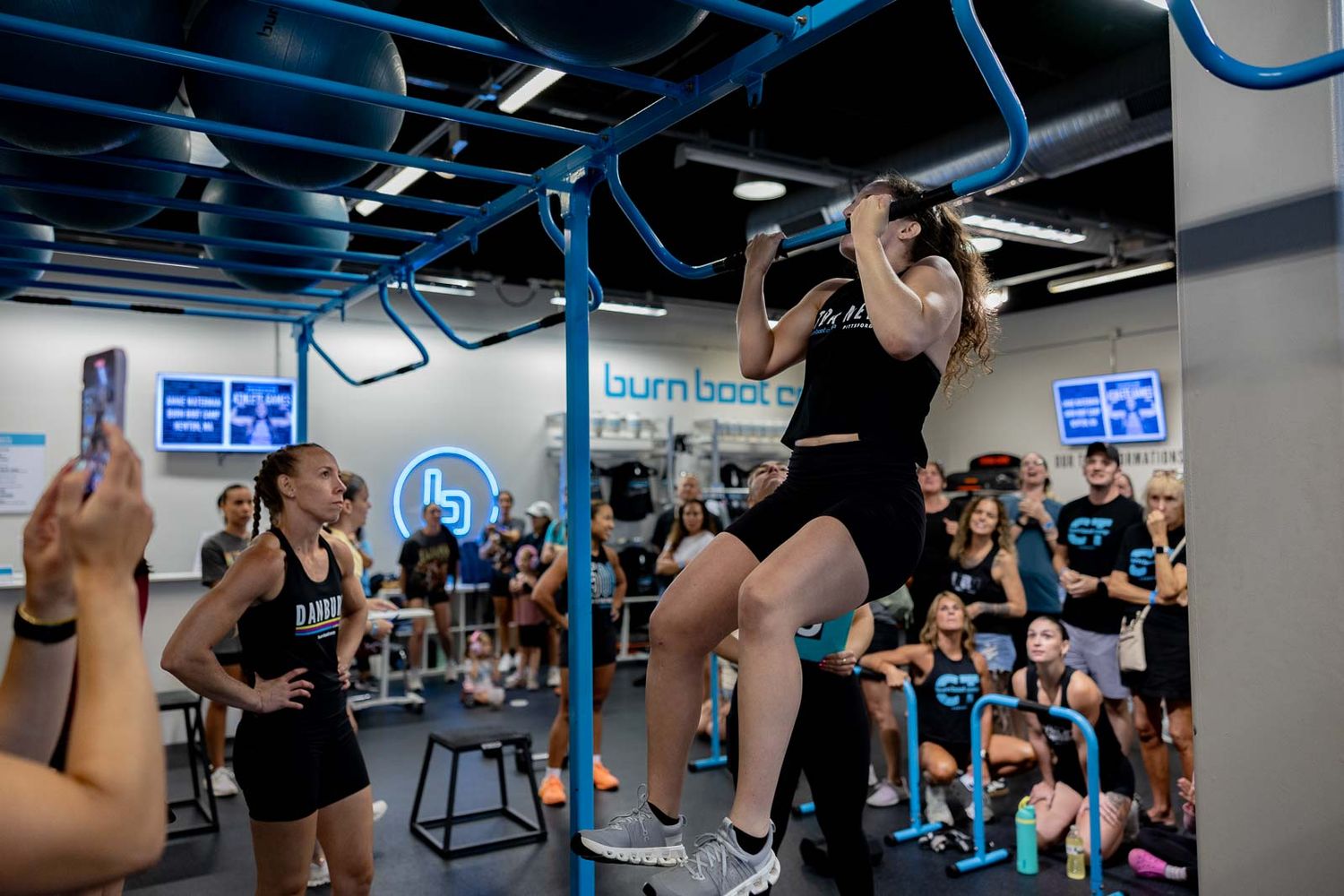 Athletic workout session in progress with participants performing pull-up exercises.