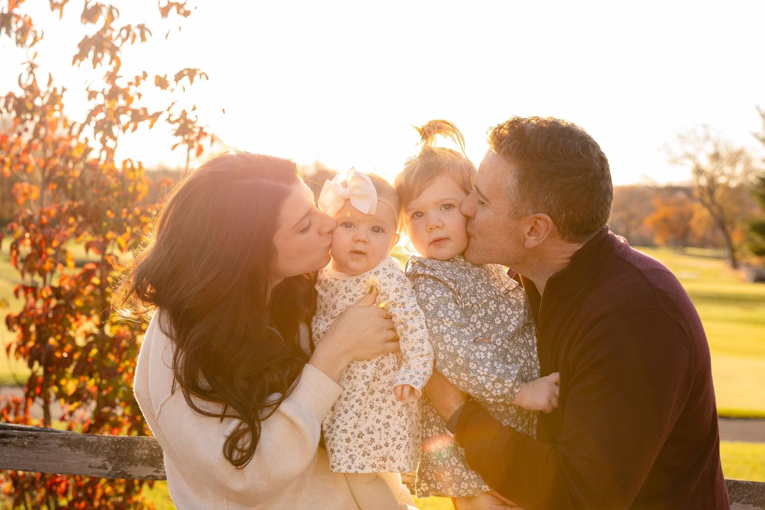 Romantic couple embraces during golden hour sunset in an autumn field with warm sunlight streaming through the trees.
