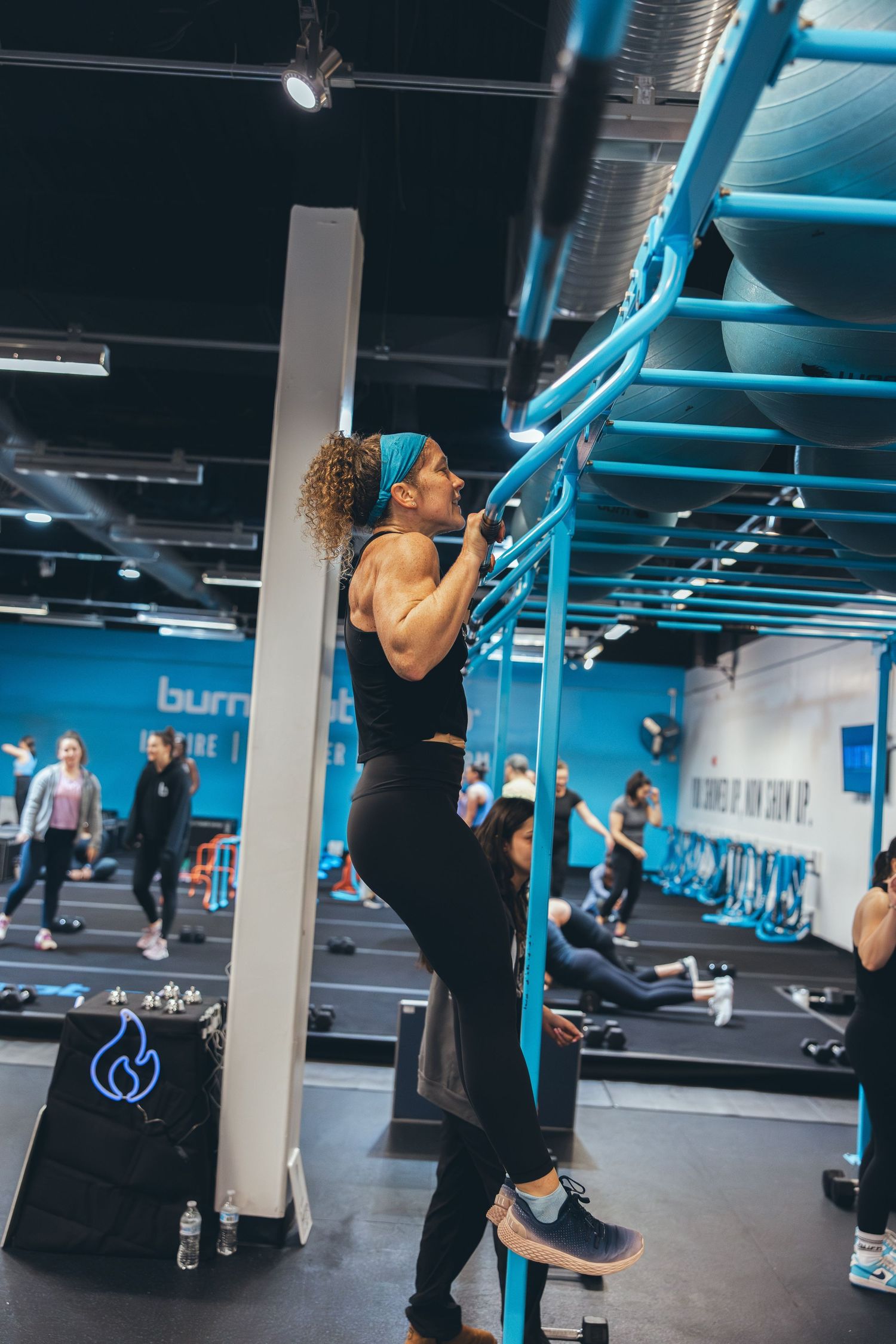 Athlete executing proper pull-up form on blue gym equipment at fitness facility.