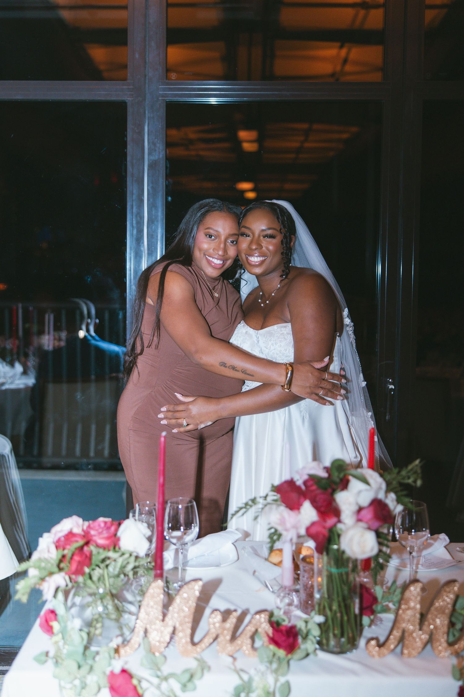Bride and friend embracing at dinner reception