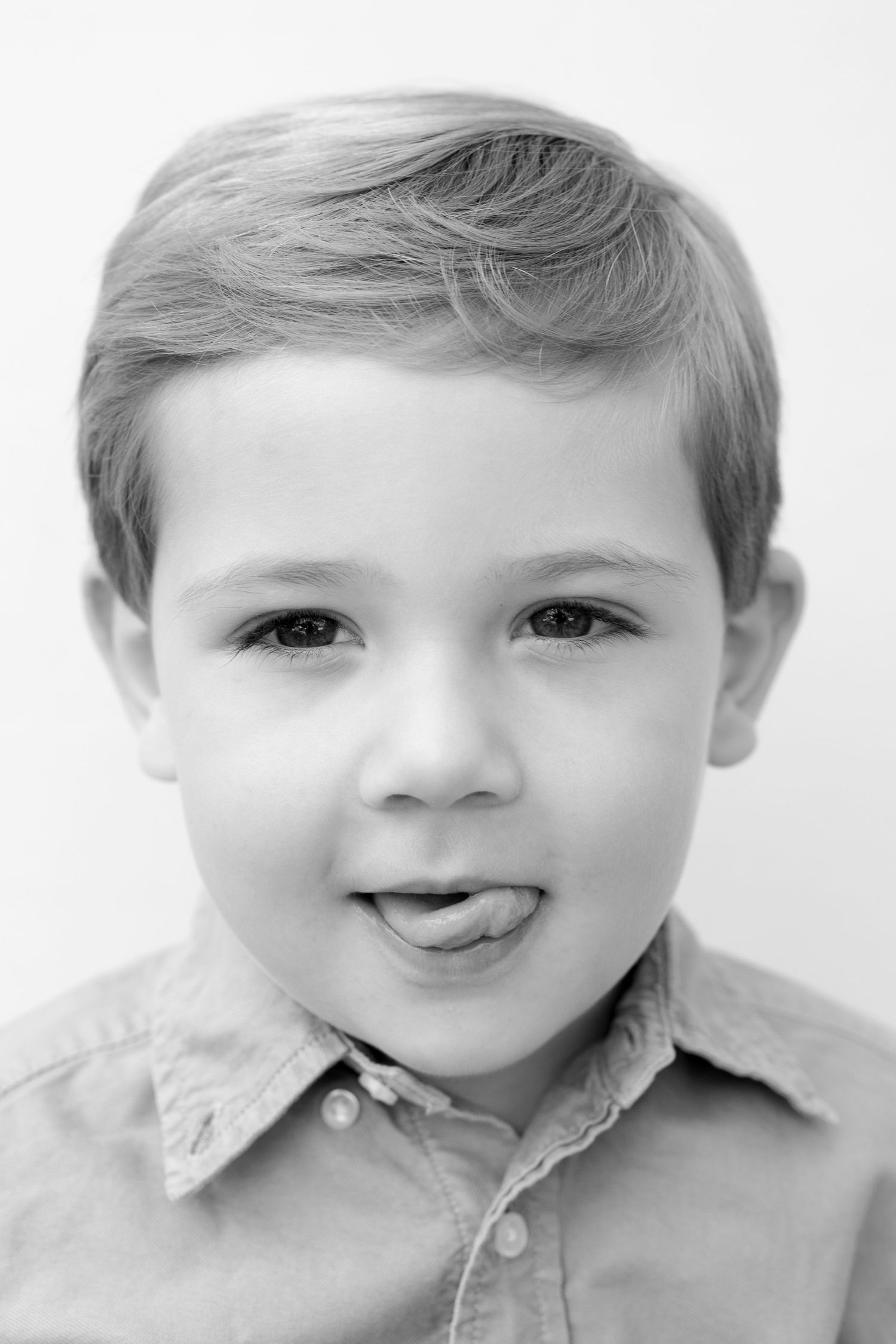A series of four black and white portraits showing a young child with a bright smile wearing a collared shirt.