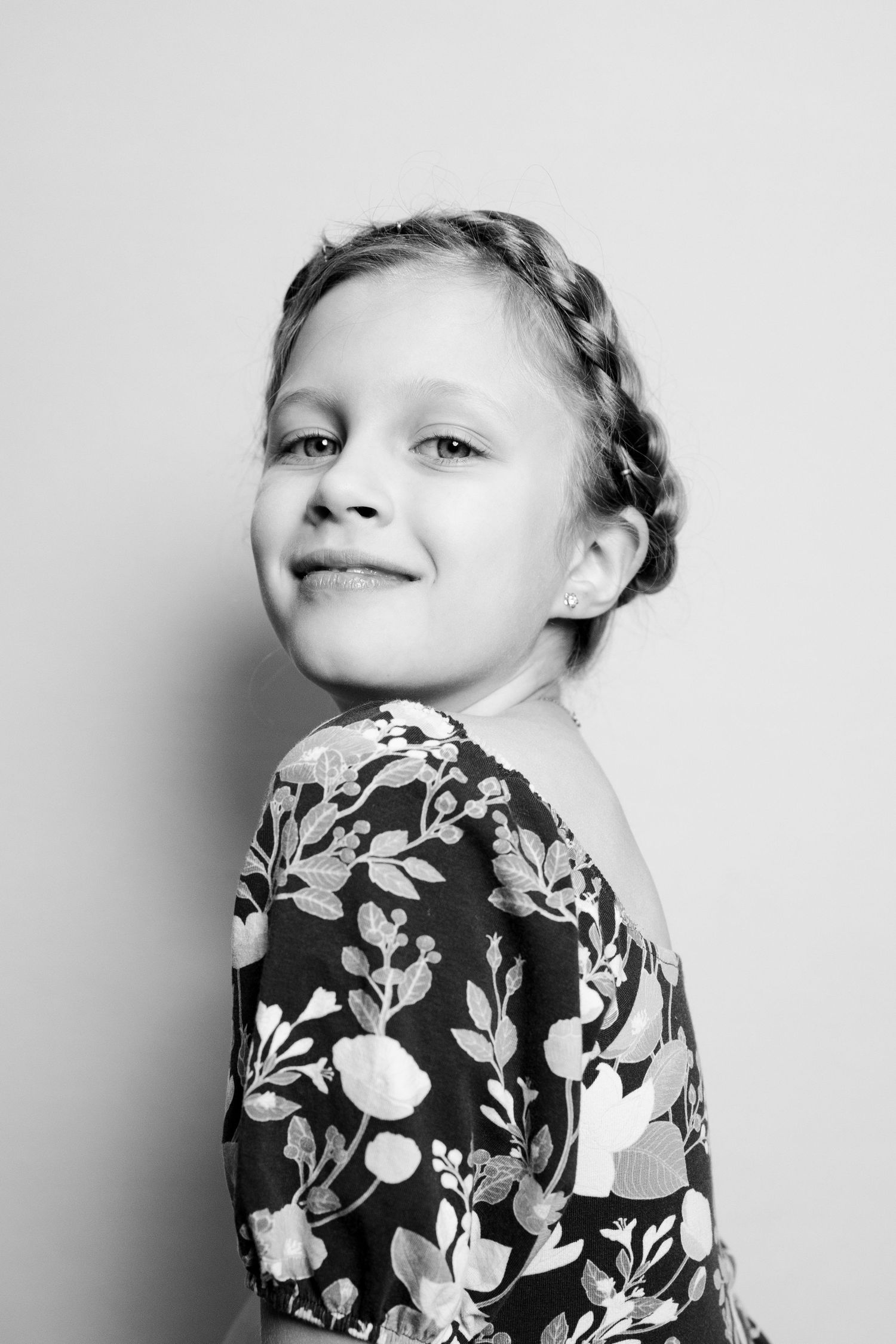 A child wearing a black and white floral dress poses expressively against a light background in a series of photos.