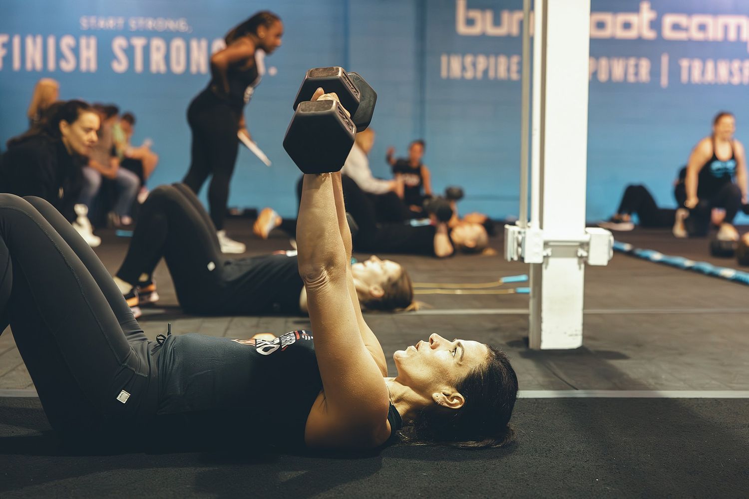 Trainer at BurnBootCamp Wilton doing chest presses