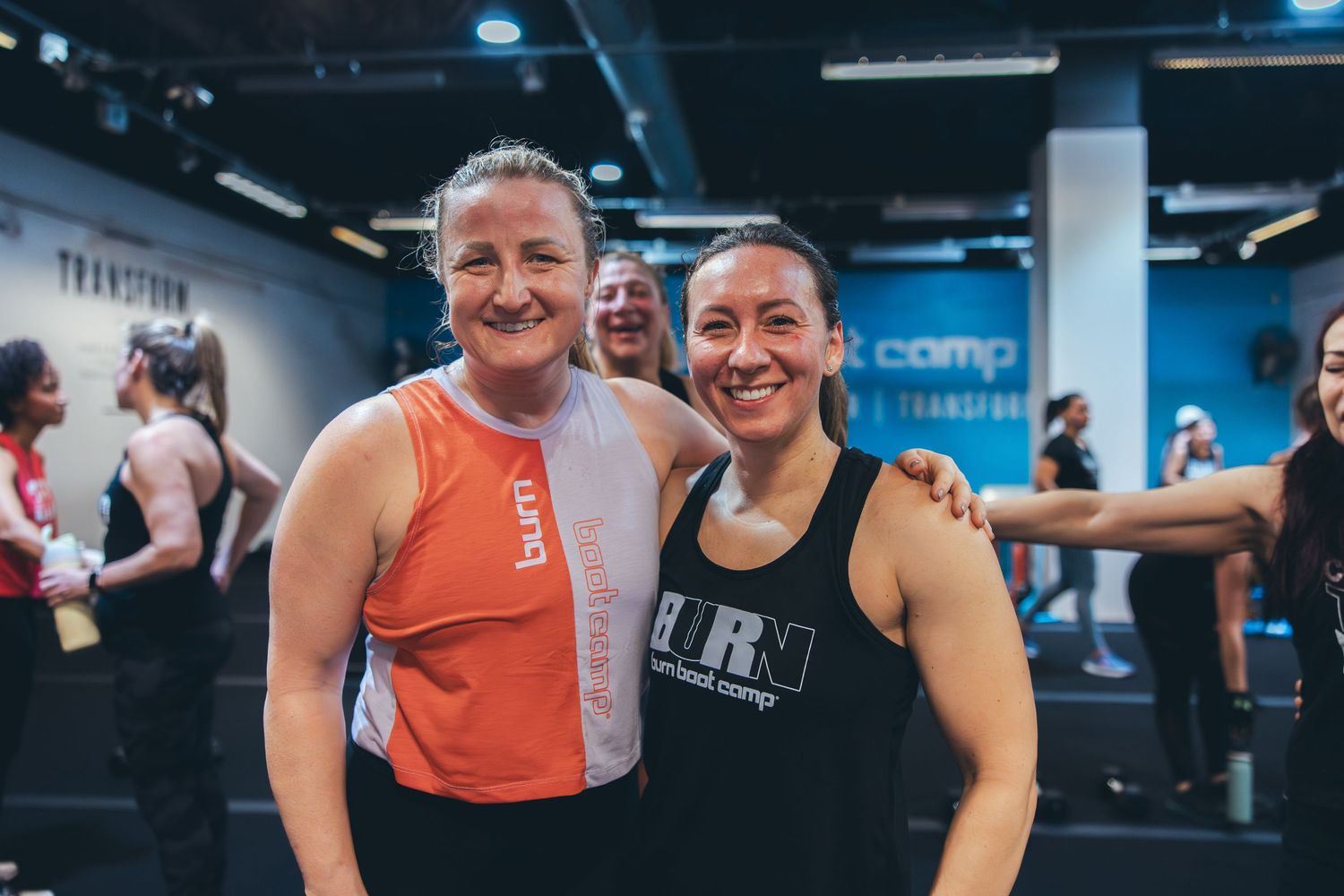 Two fitness enthusiasts in athletic wear smiling together after a workout.