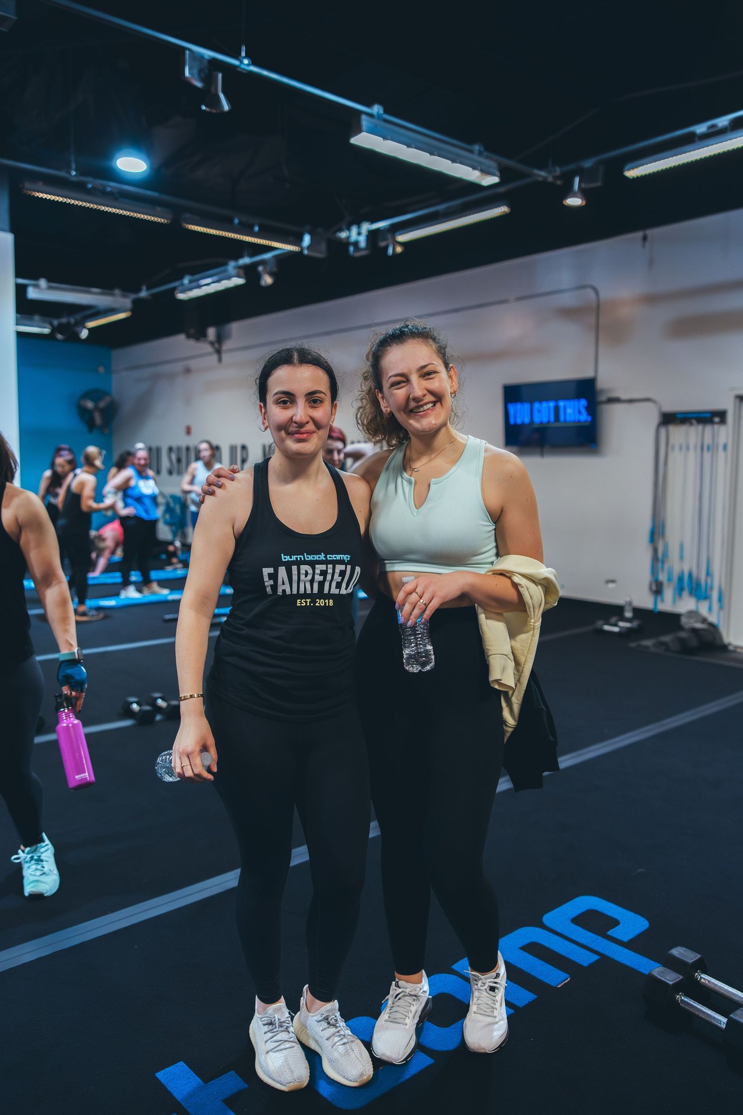 Fitness enthusiasts posing together after workout session in modern gym facility.