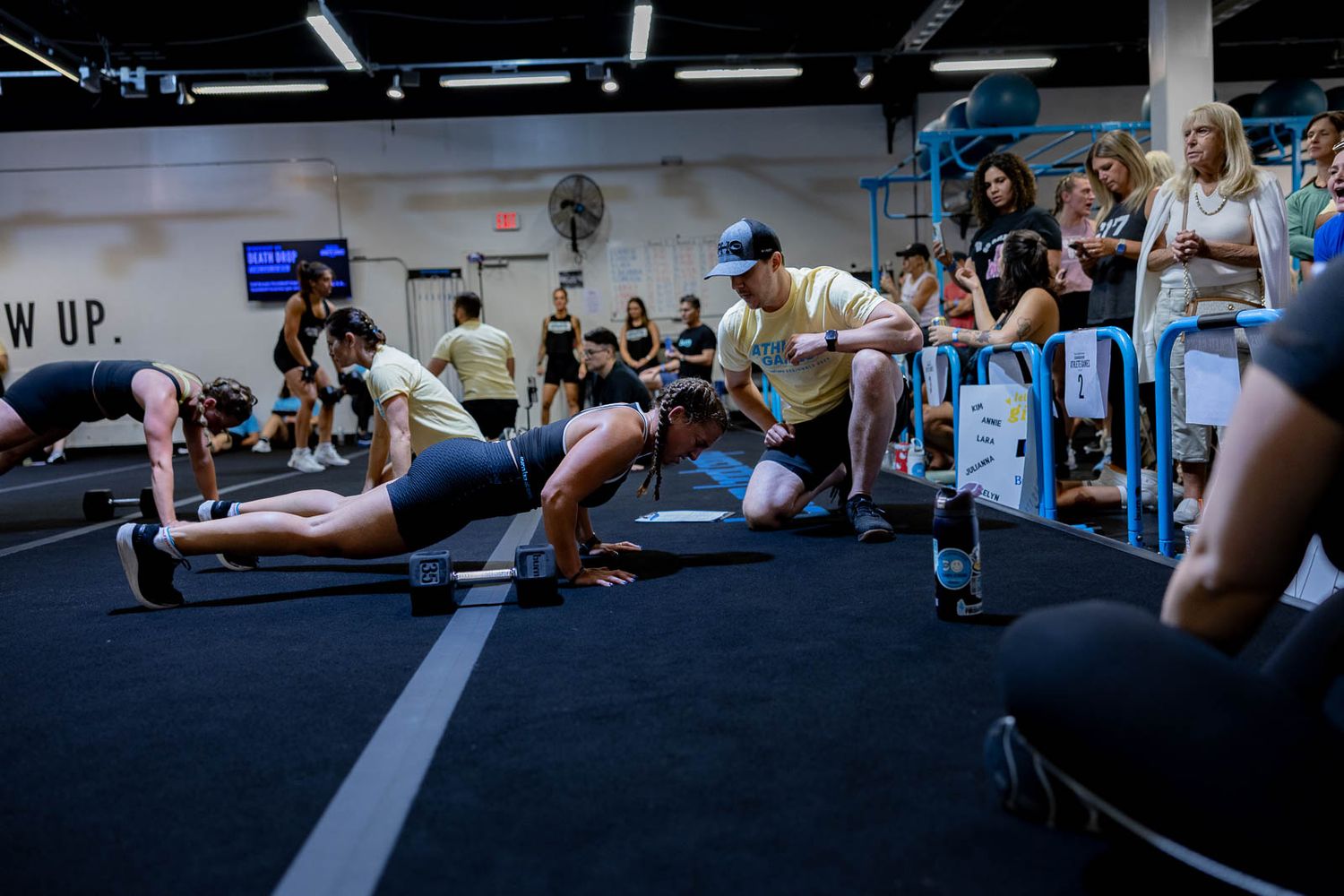 Fitness enthusiasts gather in a dark gym space while exercising together during a group workout session.