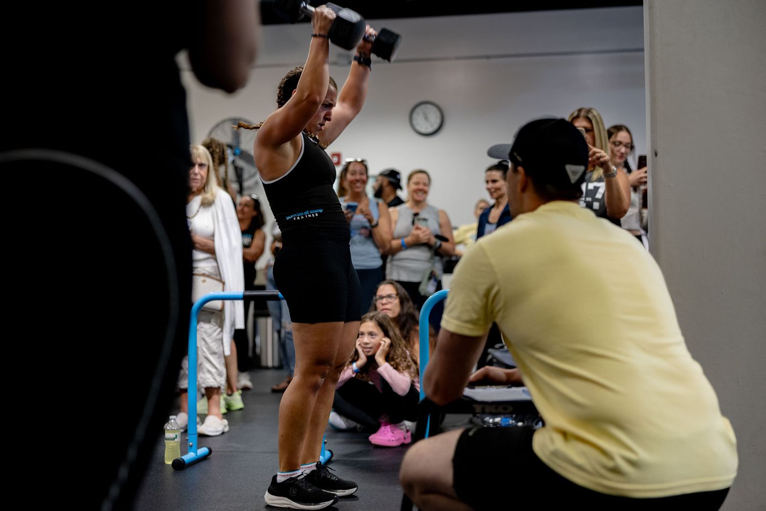 A group of athletes exercising together in a gym during an intense fitness class with weights and equipment.