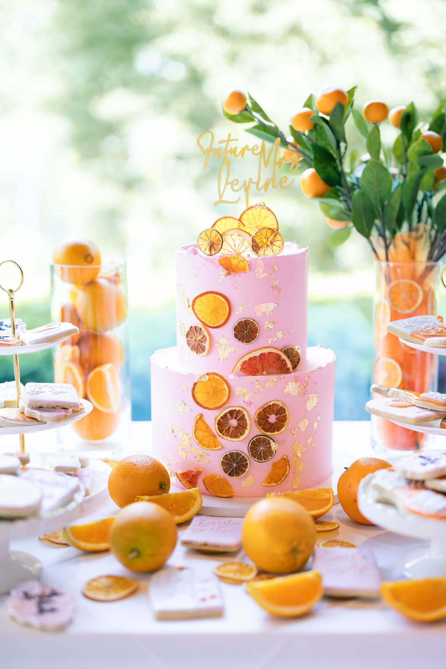 Pink lemonade garnished with fresh citrus slices and greenery sits on an elegant table setting in natural light.