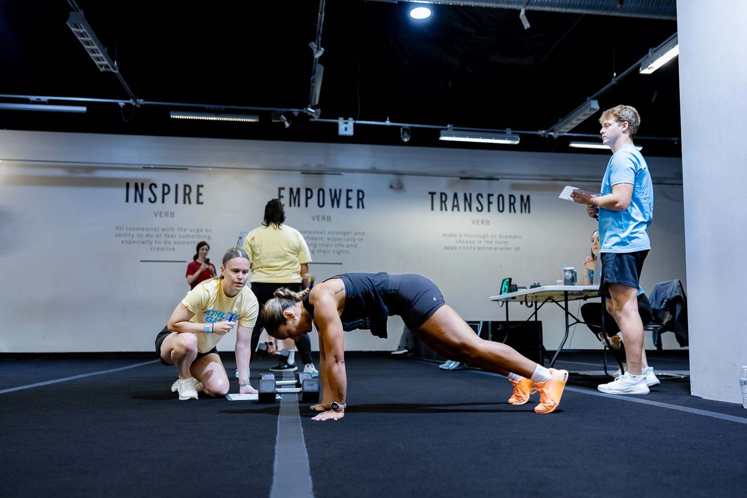 Athletes exercising in a fitness studio with Inspire and Transform text visible on the wall.