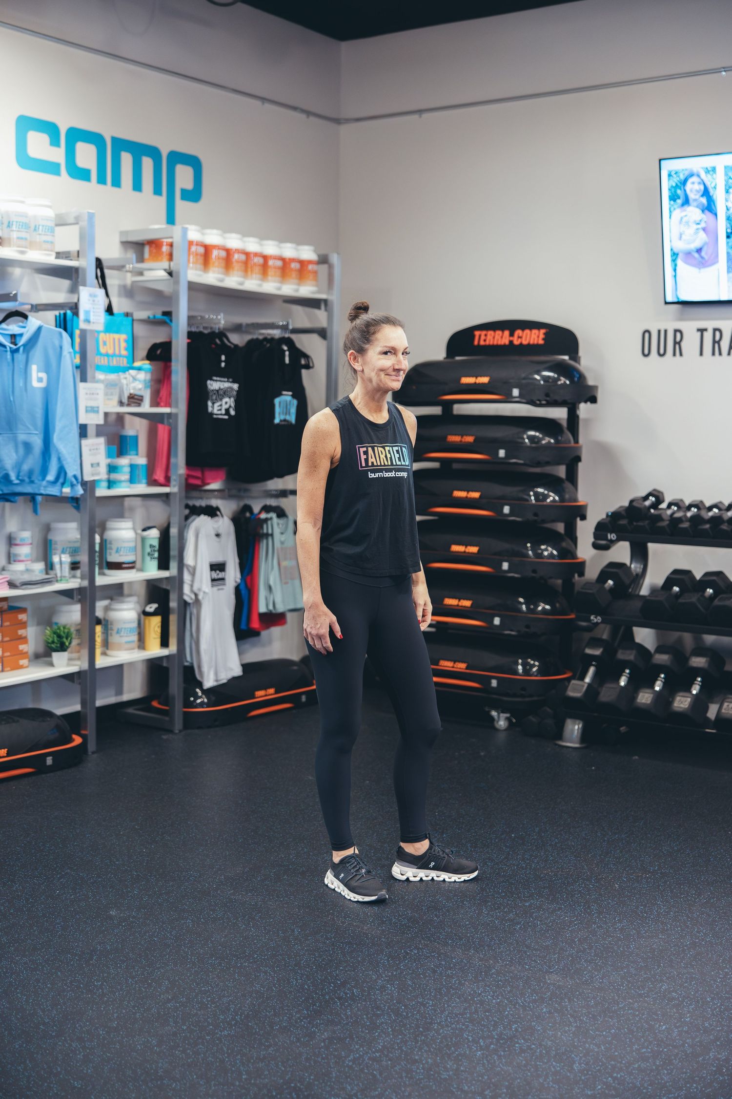 Athletic wear and fitness equipment displayed in modern gym retail area with blue Camp signage.