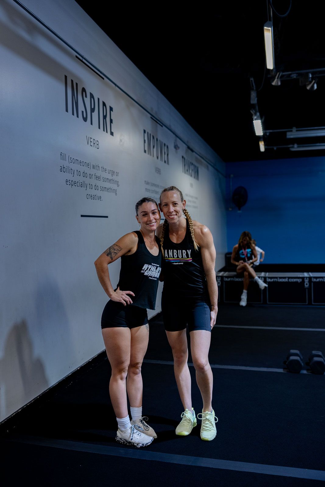 Training partners in black athletic wear posing together against a white wall with motivational text.