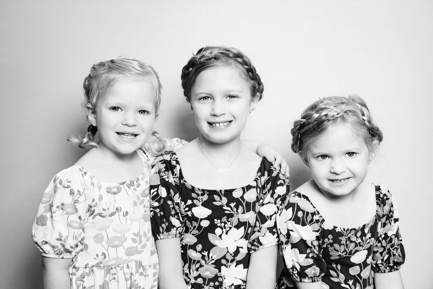 A series of black and white portraits showing joyful expressions and matching floral outfits.