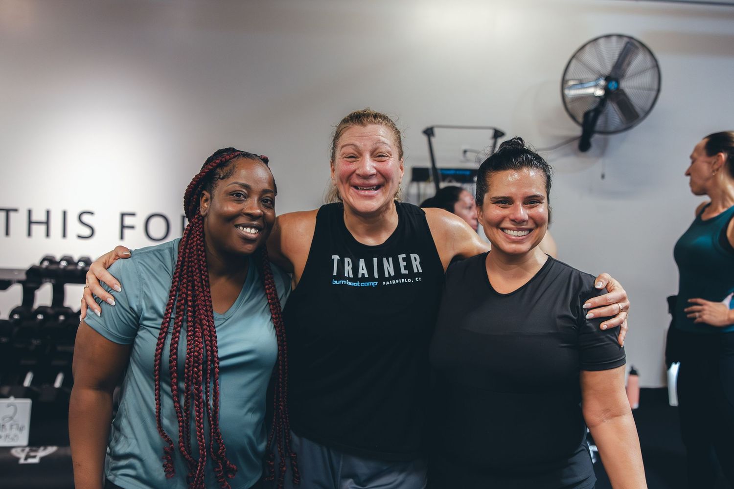 Group of friends sharing a laugh during workout break at a fitness center.