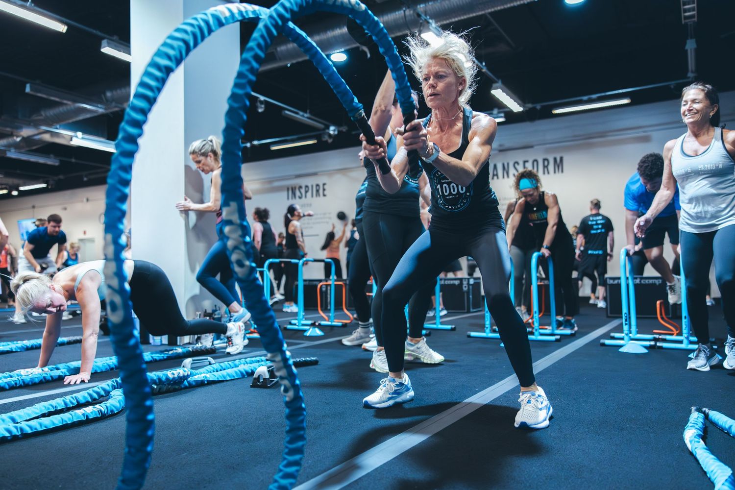 Woman performing battle rope exercises during high-intensity workout class.