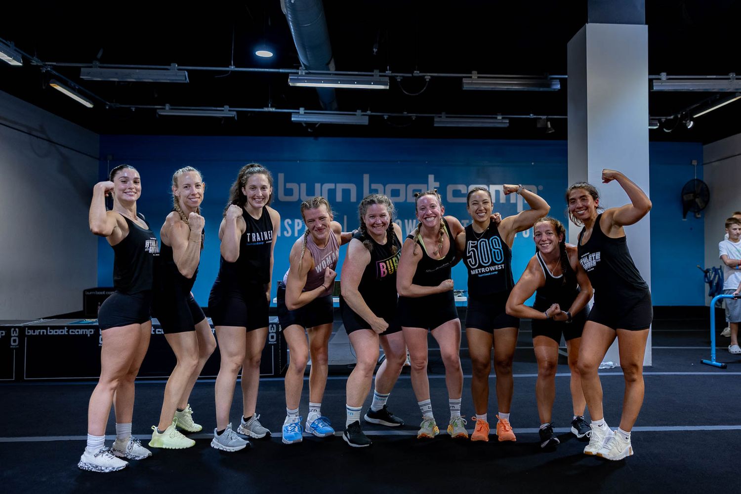 Energetic fitness group in athletic wear posing together at a Burn Boot Camp training facility.