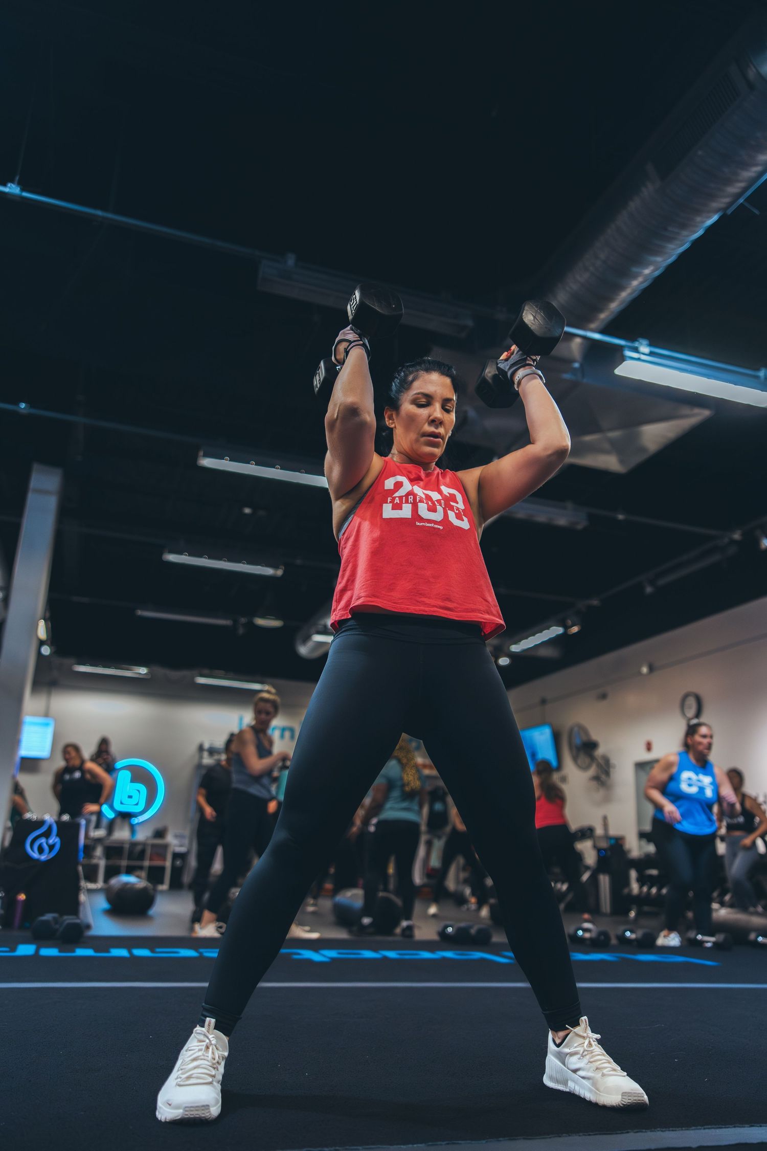 Athlete performing overhead exercise with resistance bands in crowded fitness class.