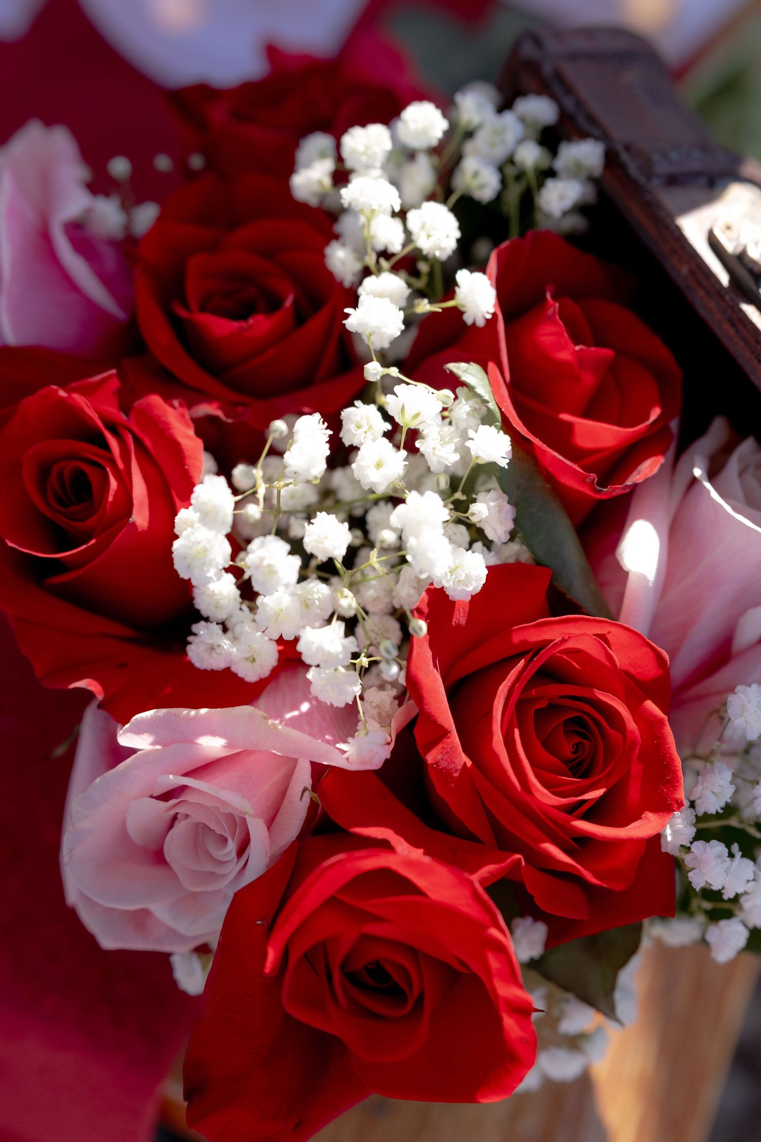 Close-up of fresh red and pink roses arranged with white baby's breath flowers.