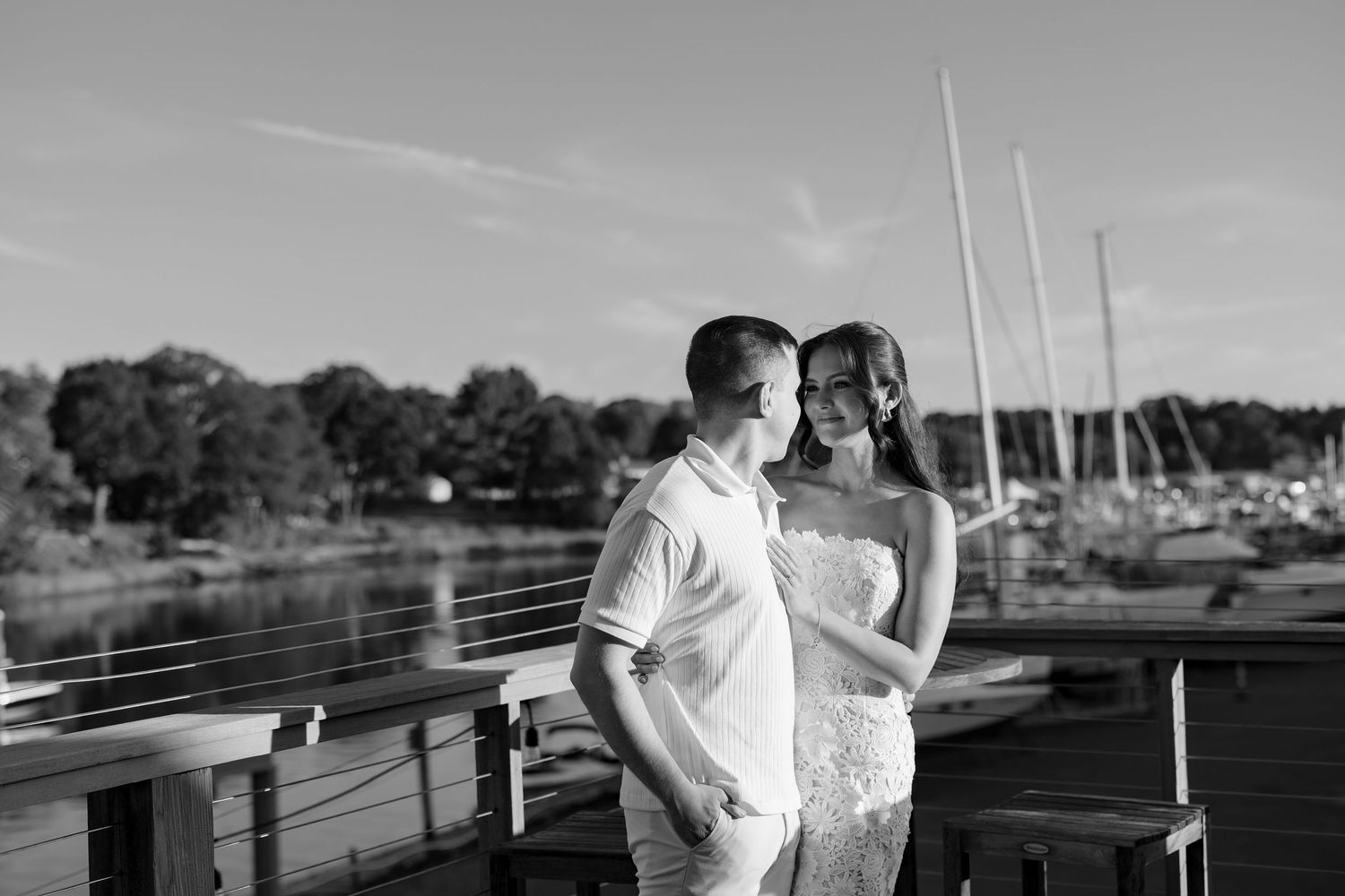 Black and white photo of couple celebrating against waterfront landscape.